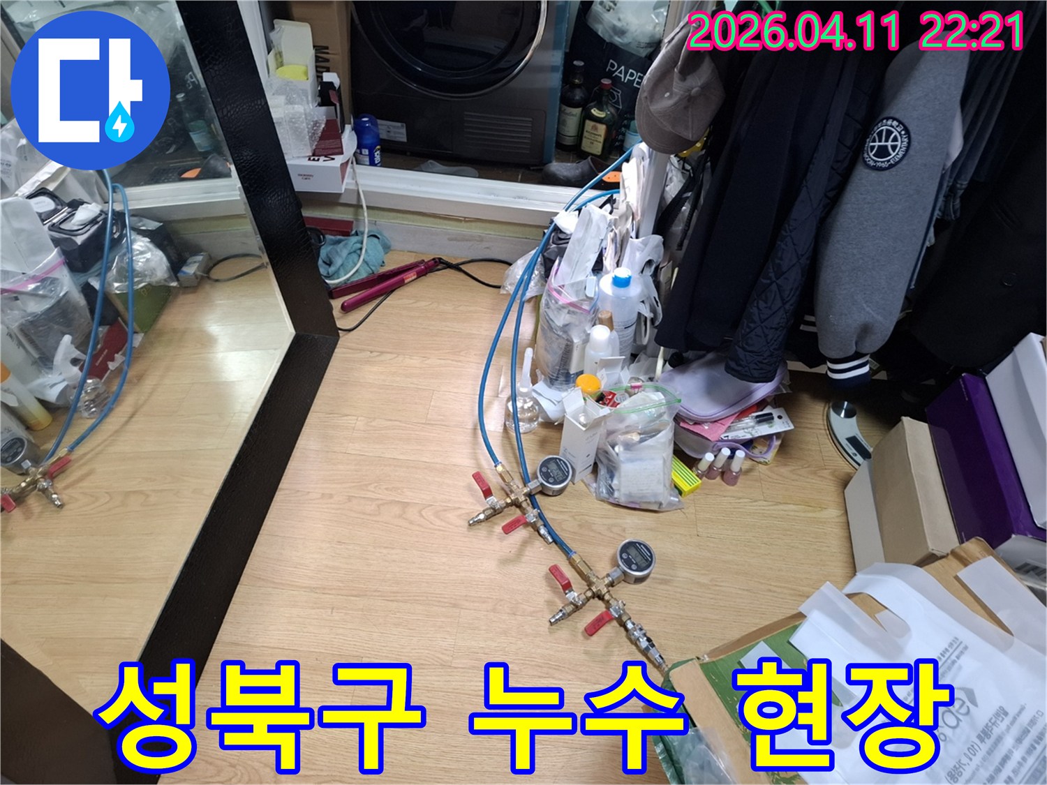 누수 탐지 전문 장비가-바닥에 놓여 있으며-배관에 연결되어-압력 검사를 진행하는-모습을 보여줍니다.