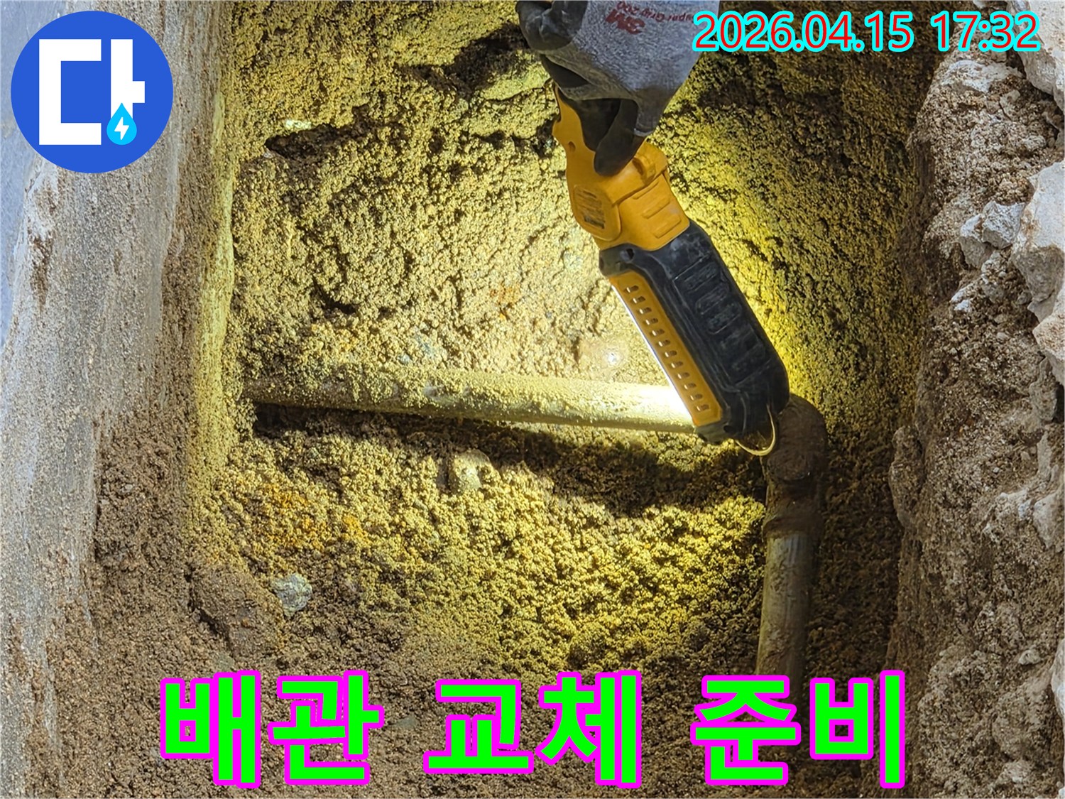 전문가가-손전등으로-땅속-배관의-누수-지점을-확인하며-교체-작업을-위한-준비를-하고-있습니다.