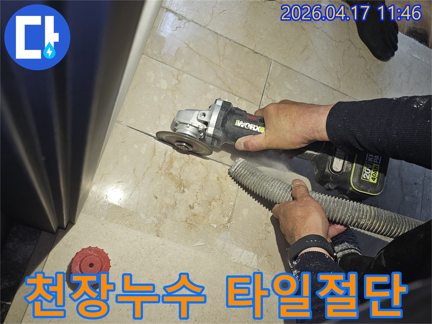 천장 누수 원인을 찾기 위해 작업자가 그라인더로 바닥 타일을 절단하고-있으며-동시에-흡진기로-먼지를-제거하여-깨끗한-작업-환경을-유지하는-모습입니다.
