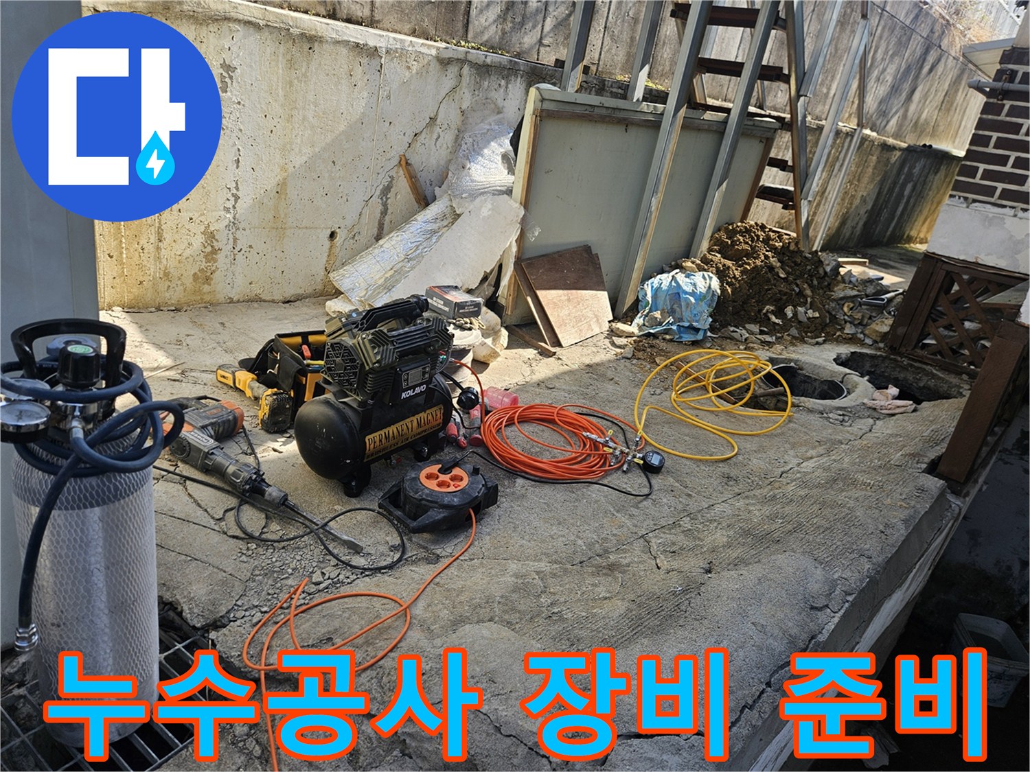 누수 공사 현장에서-에어 콤프레셔-함마드릴-호스-전선릴 등-다양한 전문 장비들이-콘크리트 바닥 위에-정돈된 채-작업 시작 전-점검을 기다리는 모습