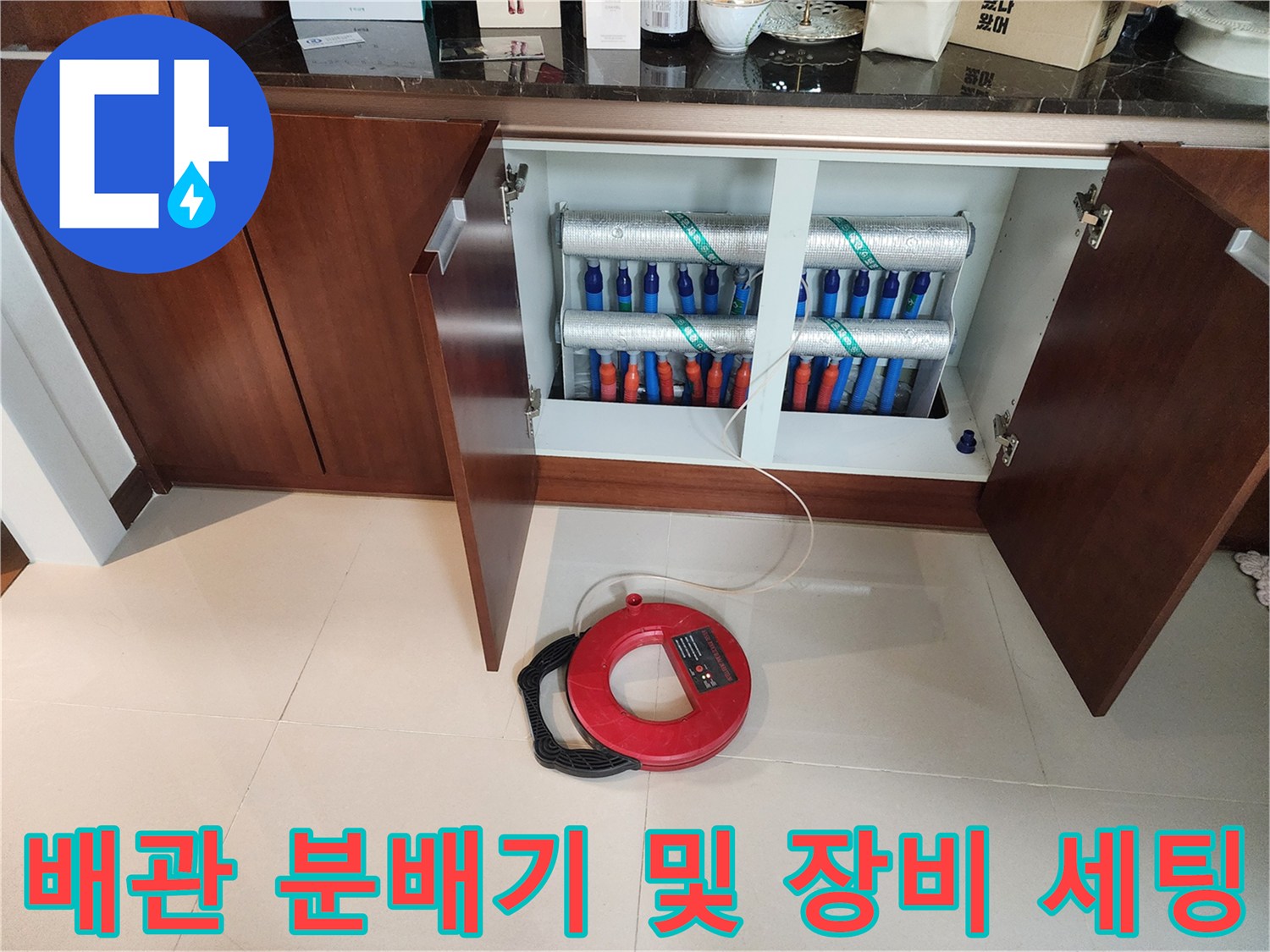 싱크대 하부 보온 배관과 바닥에 놓인 붉은색 탐지용 릴 장비
