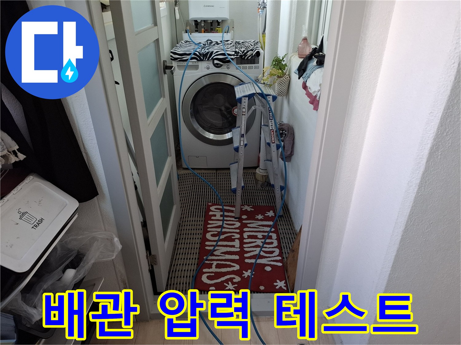 세탁실 바닥에 놓인 파란색 호스와 점검용 장비의 모습