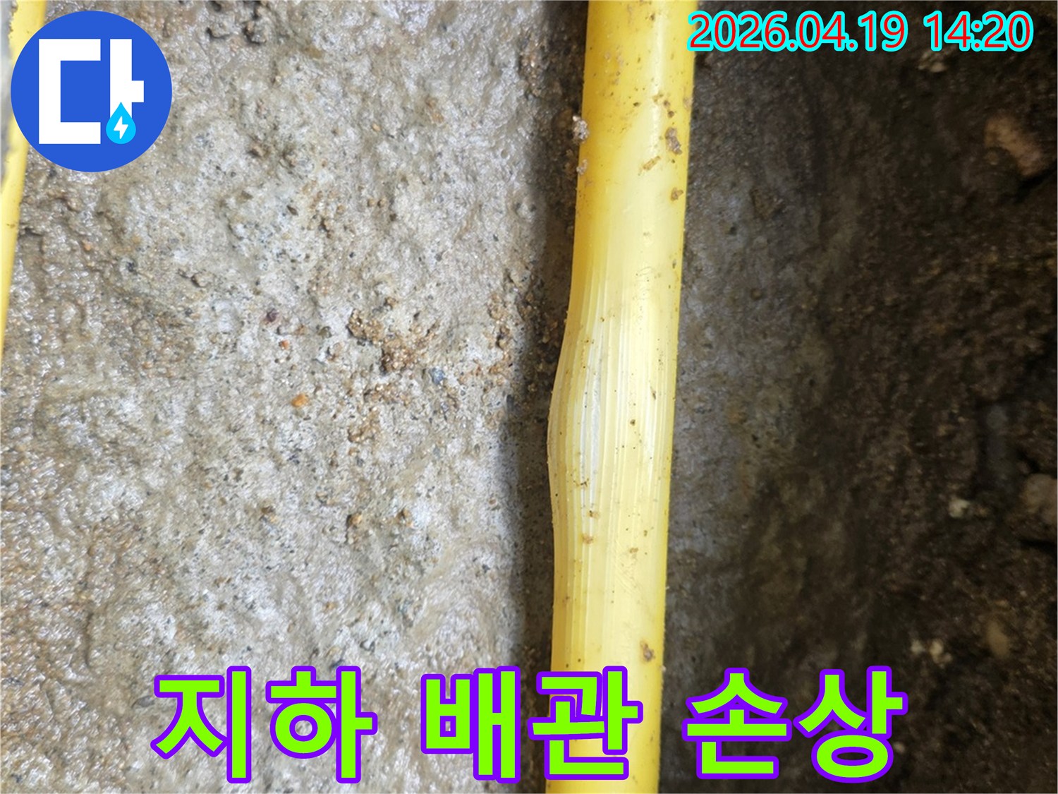 젖은 흙 속에 노출된 노란색 지하 배관의 손상 부위가-누수 발생 지점임을 명확히 보여줍니다.