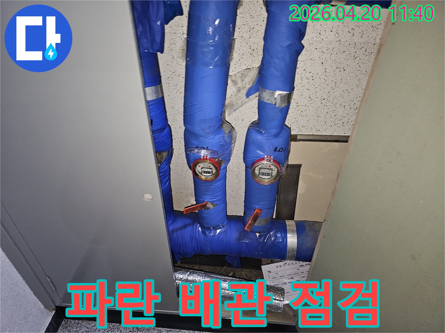 파란색으로-단열된-파이프와-두 개의-수도계량기가-설치된-공간의-누수-확인-사진입니다.