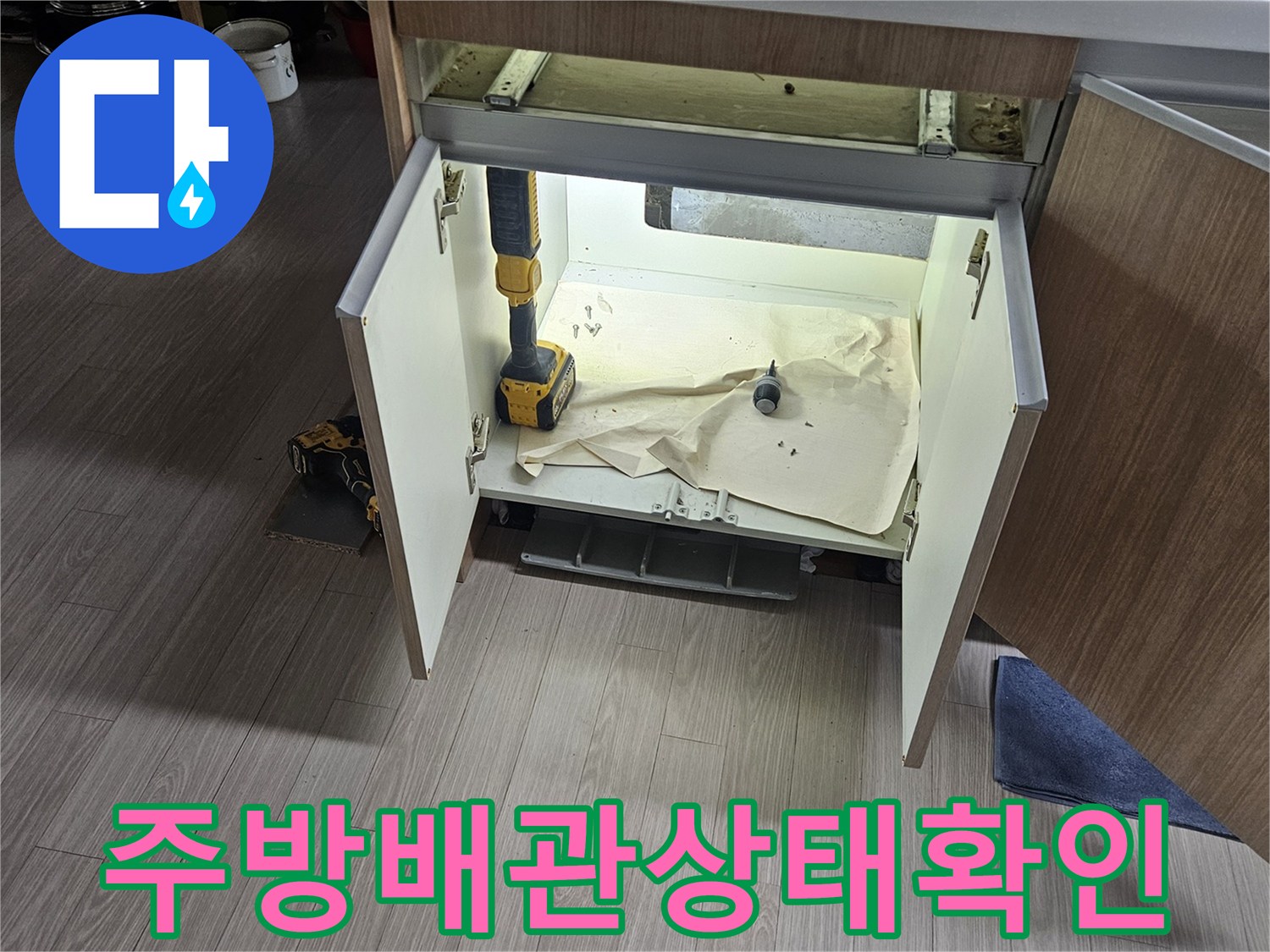 싱크대 하단 수납장 안쪽의 배관과 주변 환경을 촬영한 사진입니다.