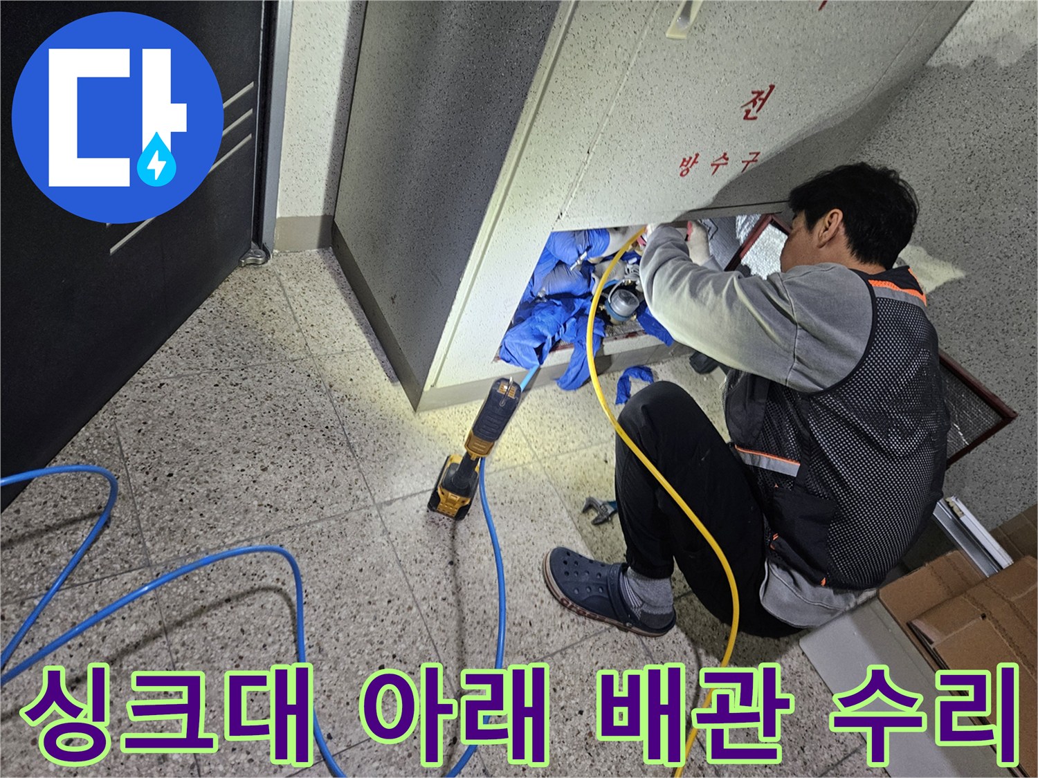 싱크대 하부 공간에서 파손된 배관을 확인하며 작업 중인 모습