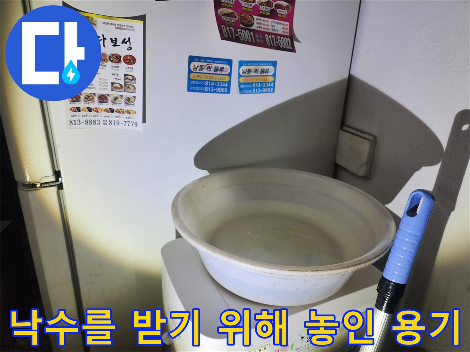 천장의 낙수를 수거하기 위해 가전제품 위에 배치된 하얀 양동이