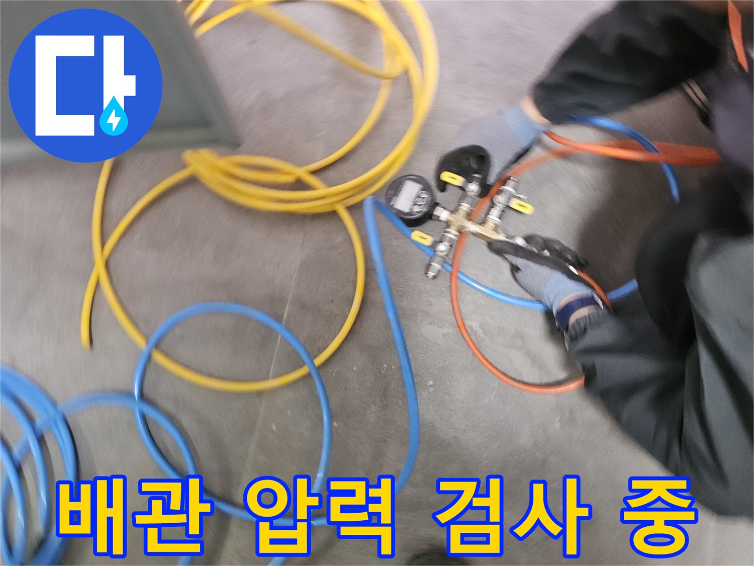 누수 탐지 엔지니어가-다양한 색상의 호스와 압력계를 사용하여-배관의 누수 여부를 확인하는-압력 검사 작업을 수행하고 있습니다