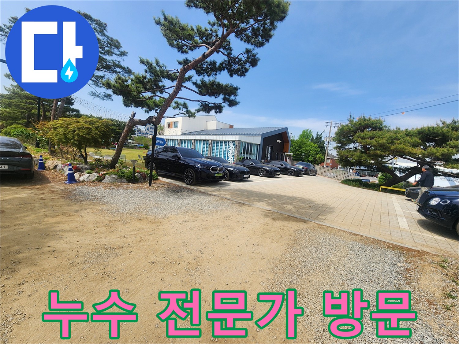 누수 문제 해결을 위해 방문한 건물의 외부 전경-주차된 차량들과 푸른 나무들이 보입니다