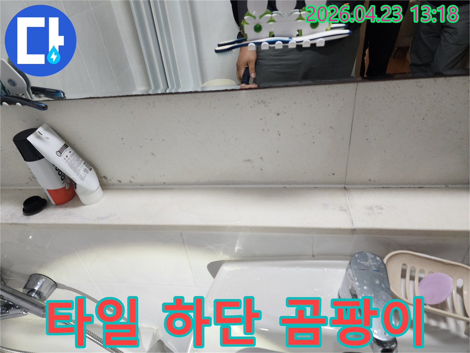 욕실 벽면 타일 하단에 나타난-지속적인 습기로 인한-검은색 곰팡이와 물 얼룩을 보여주는 사진