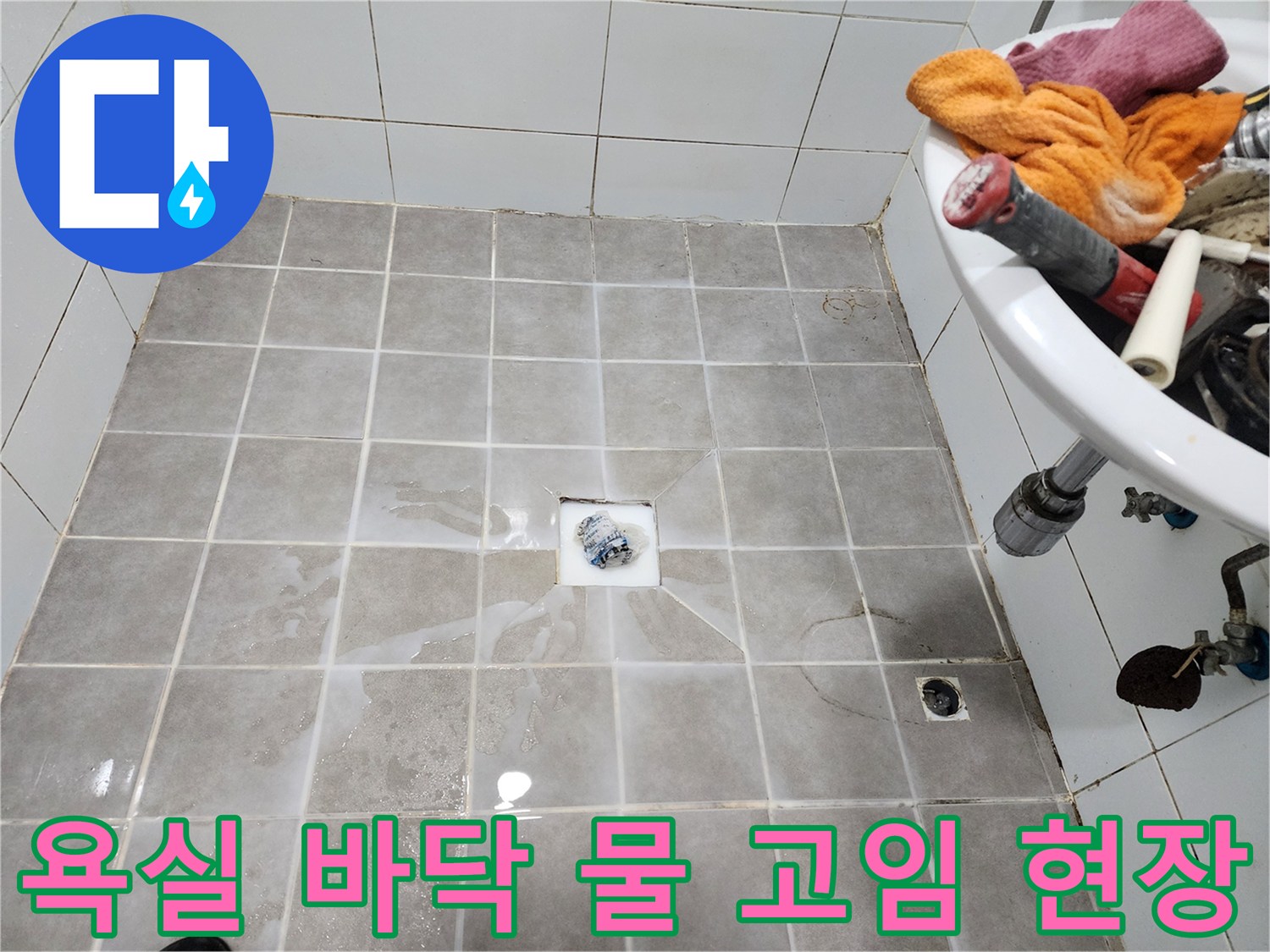 욕실 바닥 타일 위에-물이 흥건하게 고여-누수 문제를 보여주는-현장 점검 사진입니다