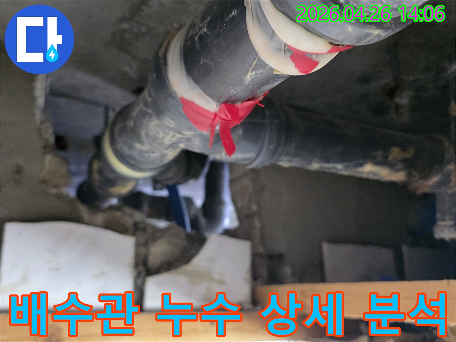 이 이미지는 아파트 배수관에서-누수 지점을 빨간 테이프로 표시하고-그 주변을 면밀히 관찰하며-상세 분석을 진행하는-전문가의 모습을 보여줍니다.