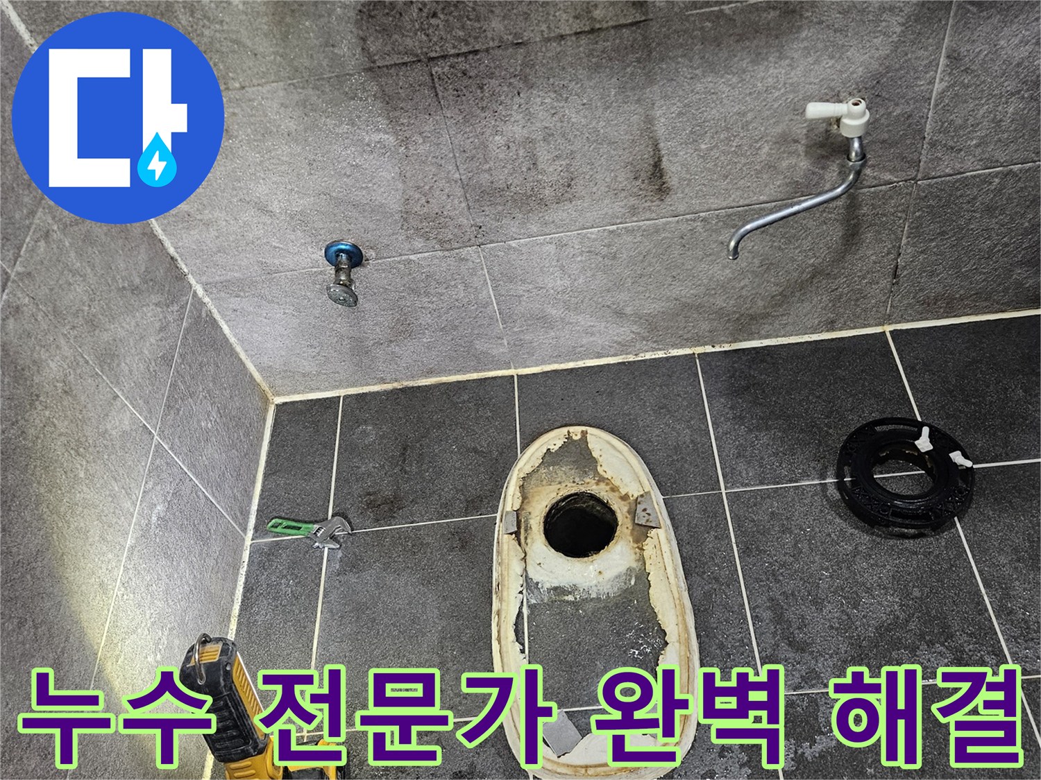 변기가 제거된 욕실 바닥의 배수구와-주변 타일에 스며든 물의 흔적을-손전등으로 밝혀 누수 전문가가 완벽한 해결을 위해 현장을 확인하는 모습입니다.