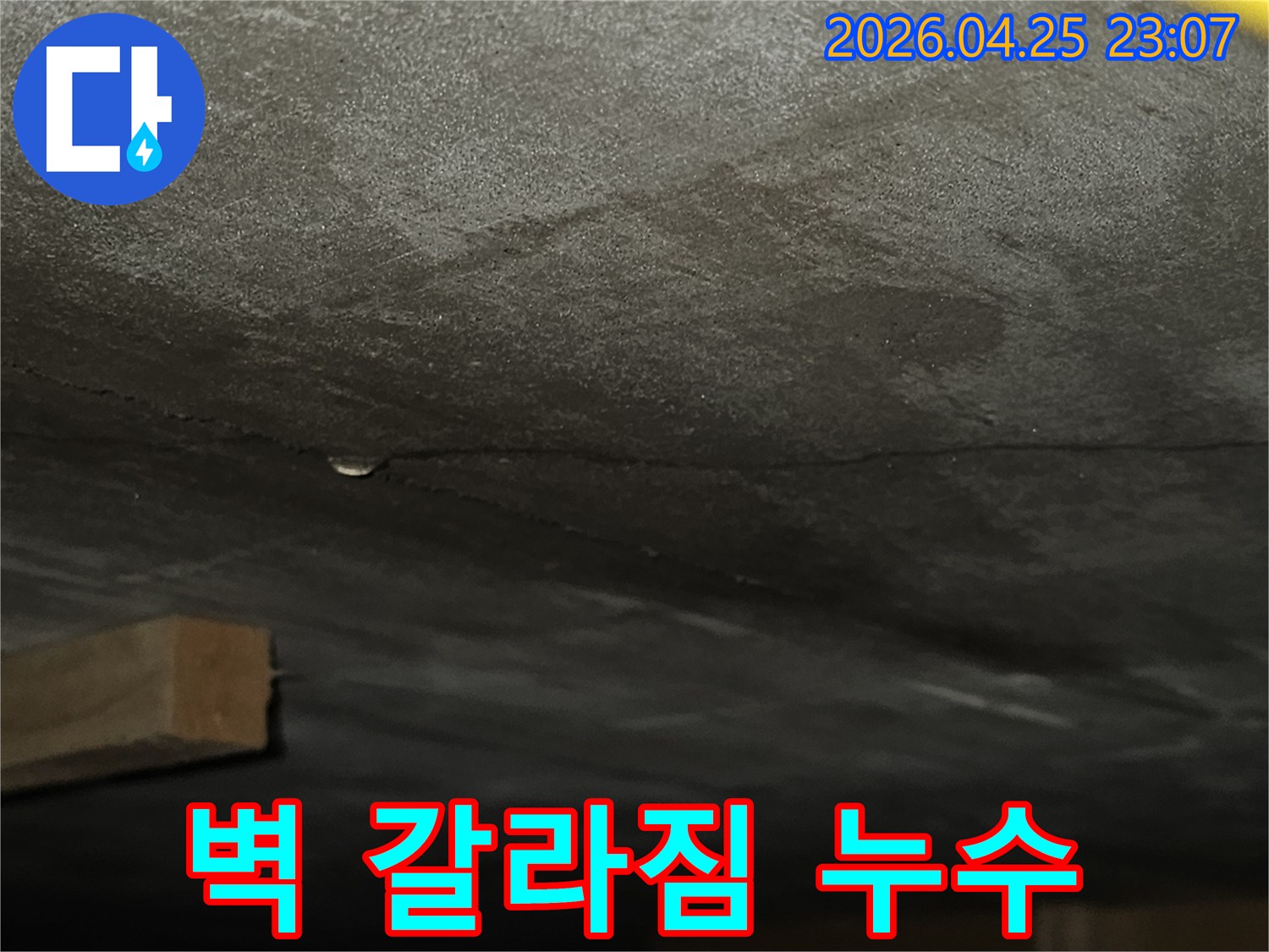 콘크리트 벽의 길고 얇은 균열을 따라 물기가 스며들어 어두워진-누수 현장의 모습