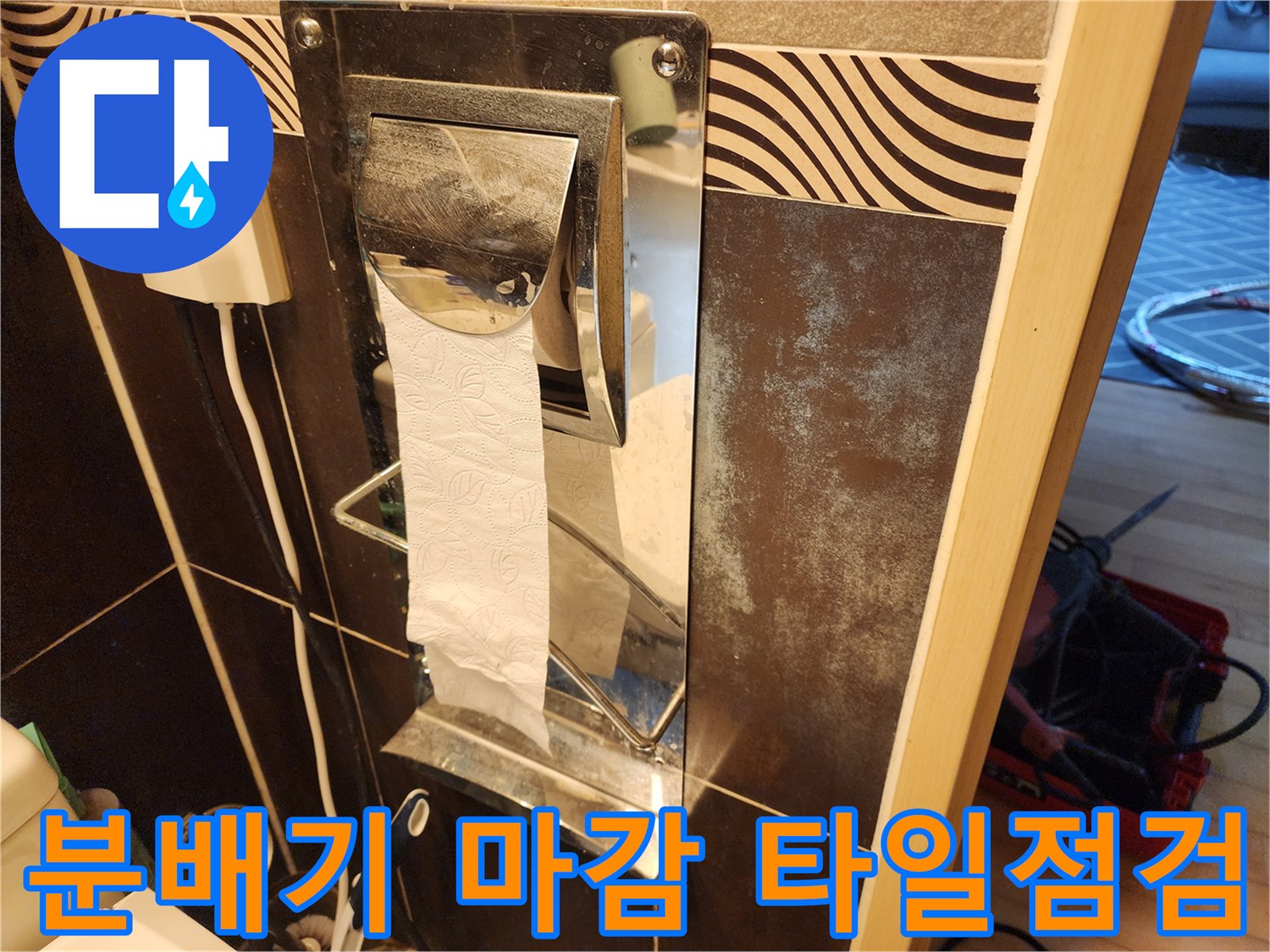 화장실 분배기 마감 후-주변 타일의-상태와-오염 여부를-면밀히-점검하는-모습을-담은-사진입니다.