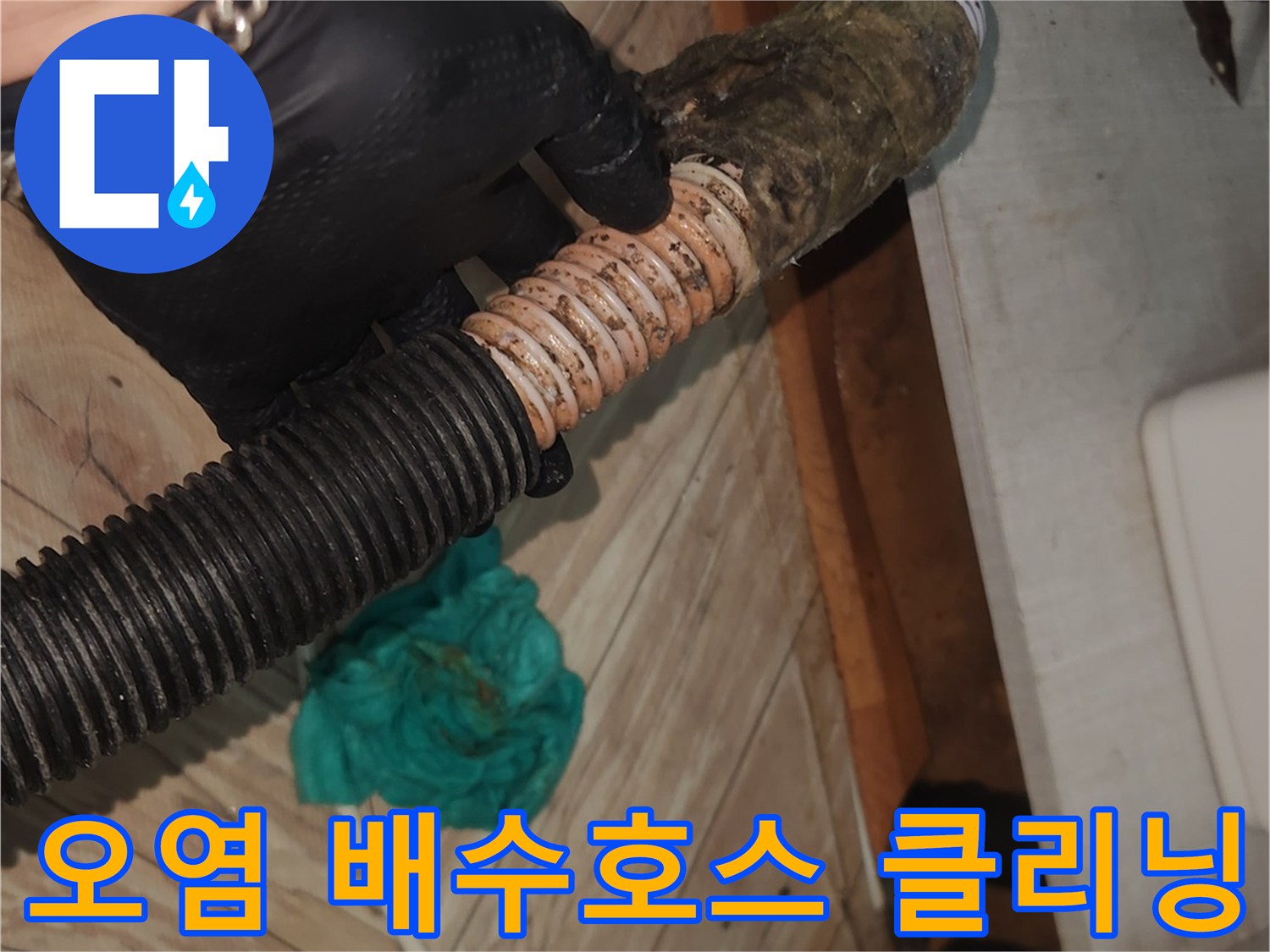 전문 엔지니어가-검은색 작업 장갑을 착용하고-오랜 사용으로 오염된 싱크대 배수 호스를-꼼꼼하게 점검하는 현장 사진