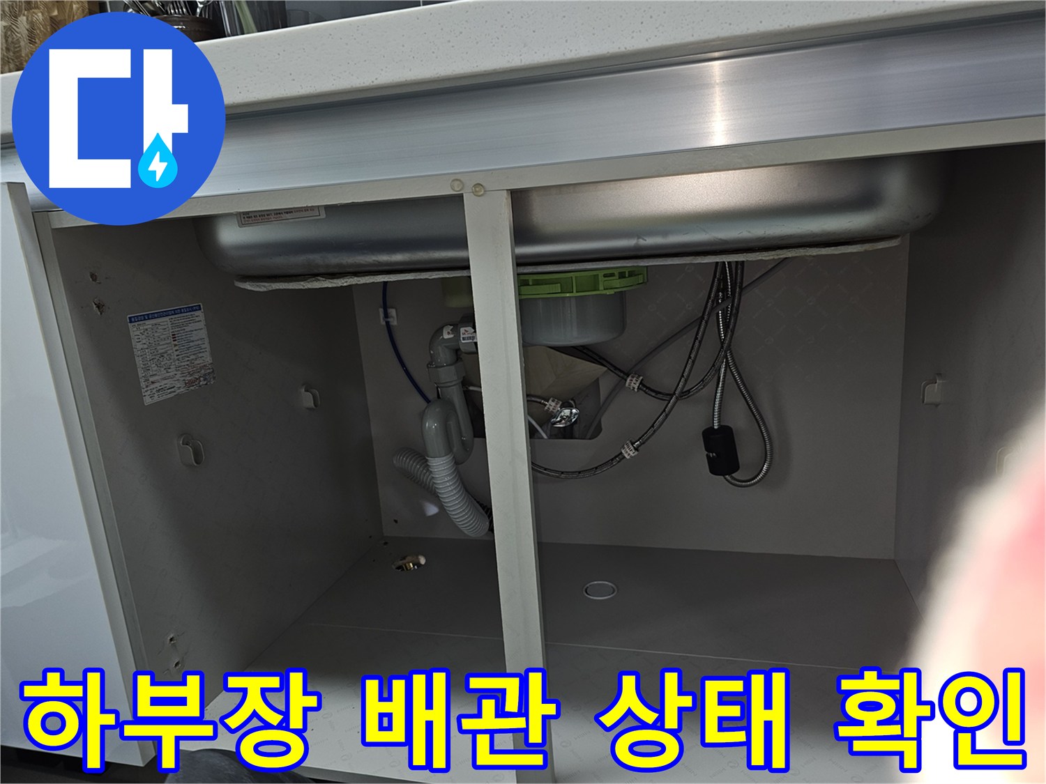 싱크대 하부장 내부의 다양한 배관과 호스들이 연결된 모습을 보여줍니다-누수 여부를 확인하기 위한 정밀 검사 중입니다.