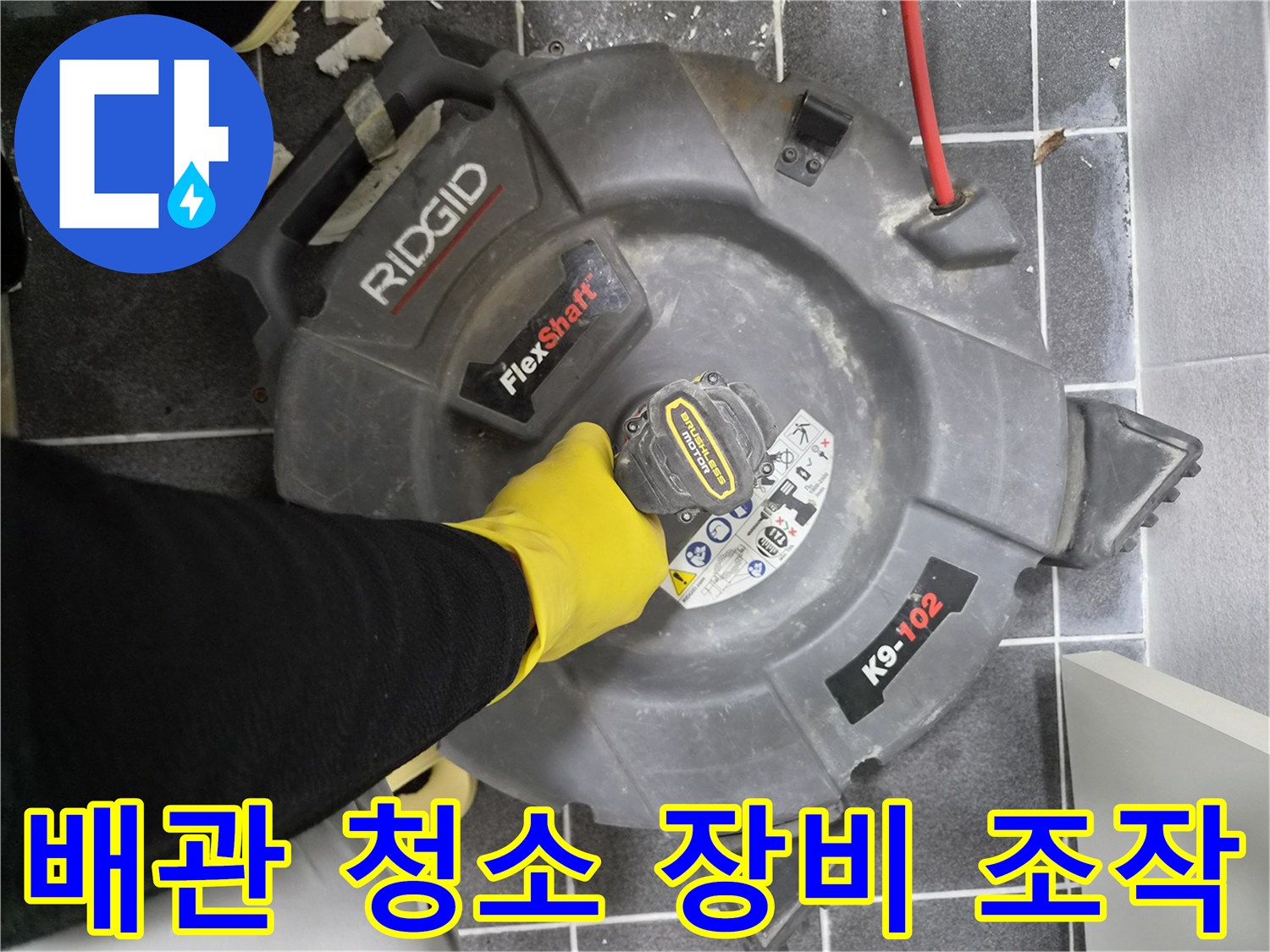 작업자가-노란색 고무장갑을 끼고-리지드 플렉스샤프트 K9-102 장비를 이용하여-배관 내부를 청소하는 장면입니다.