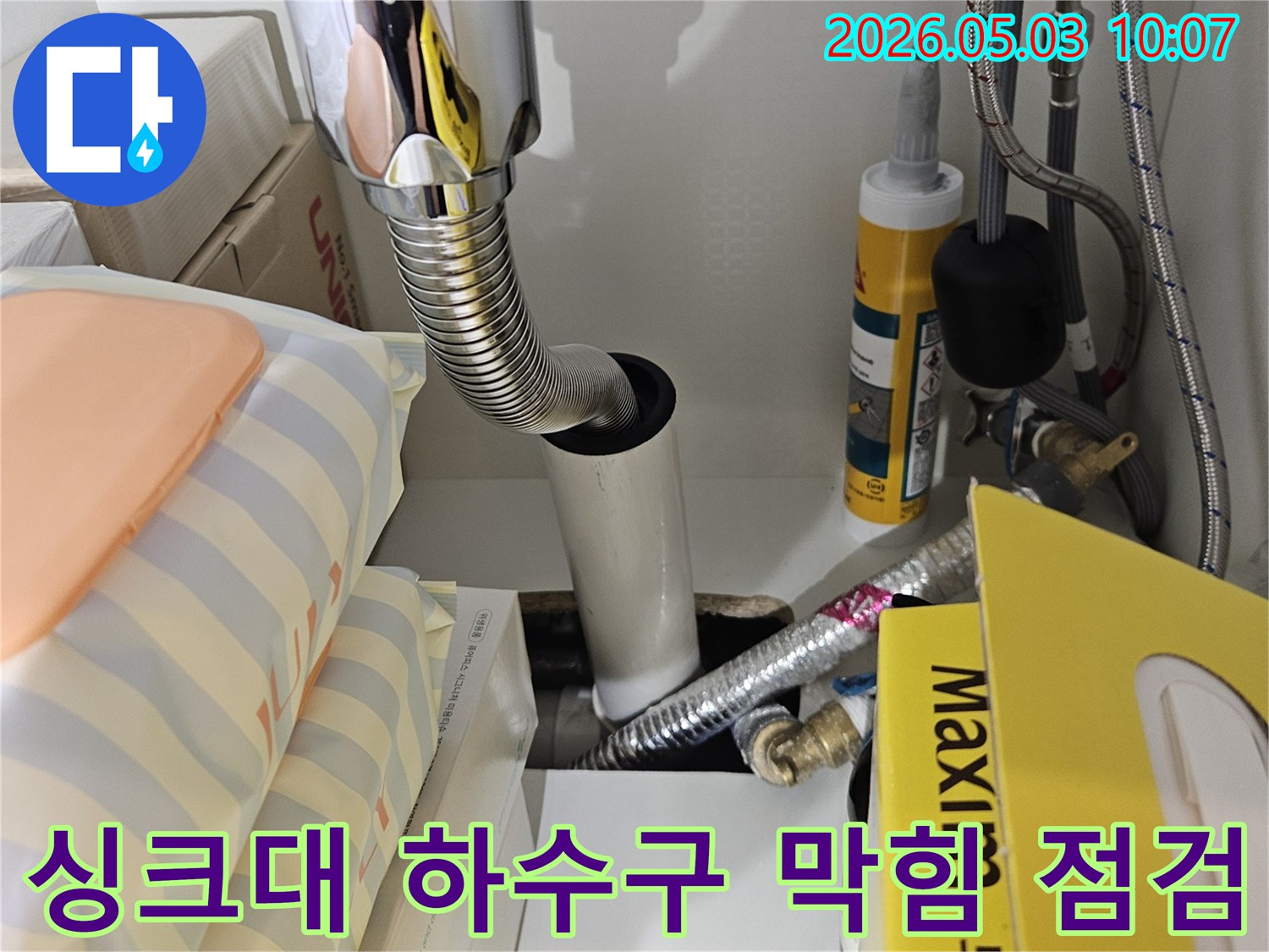 싱크대 하부의 배수관 연결 부위와-유연한 호스 주변을 집중적으로 점검하여 누수 원인을 찾는 모습