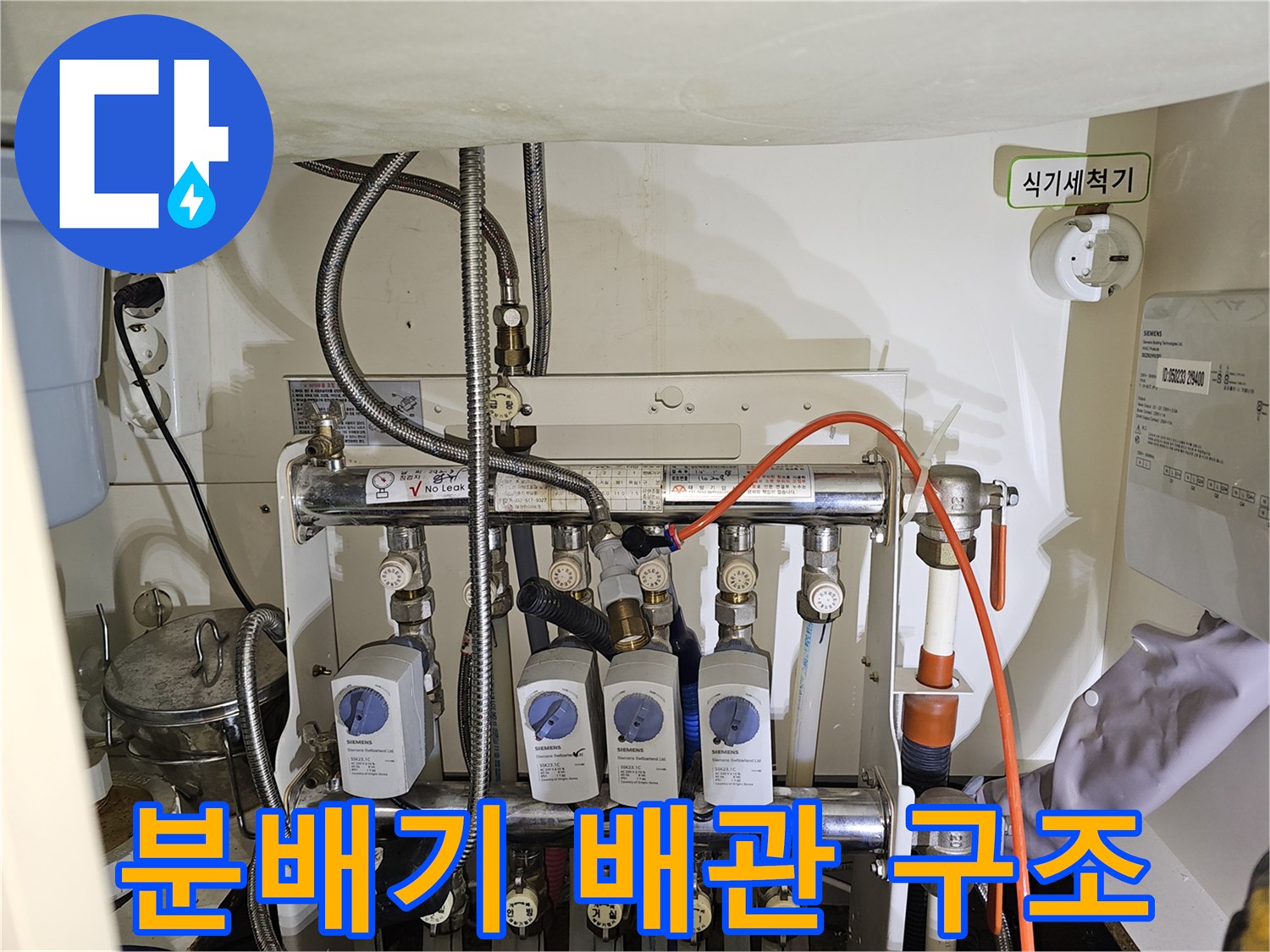 싱크대 밑에 복잡하게 연결된 분배기와 각종 제어 밸브들