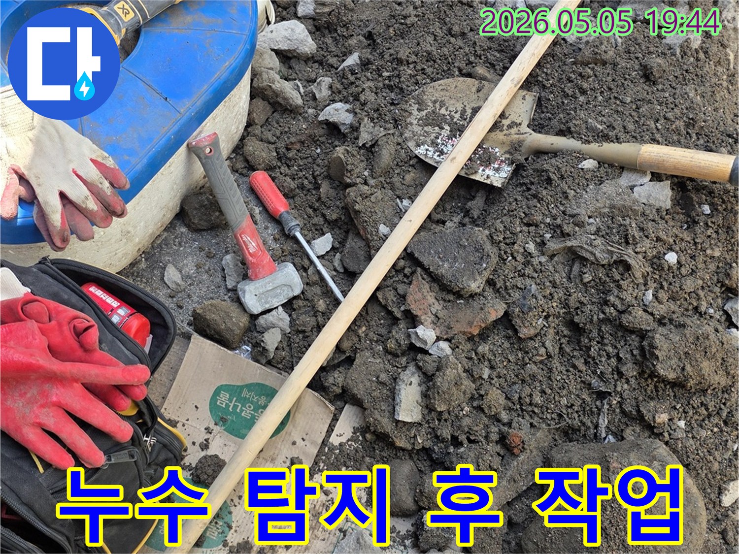 누수 현장에서 발견된 흙과 돌-그리고 배관 수리를 위한 공구들이 함께 놓여 있습니다.