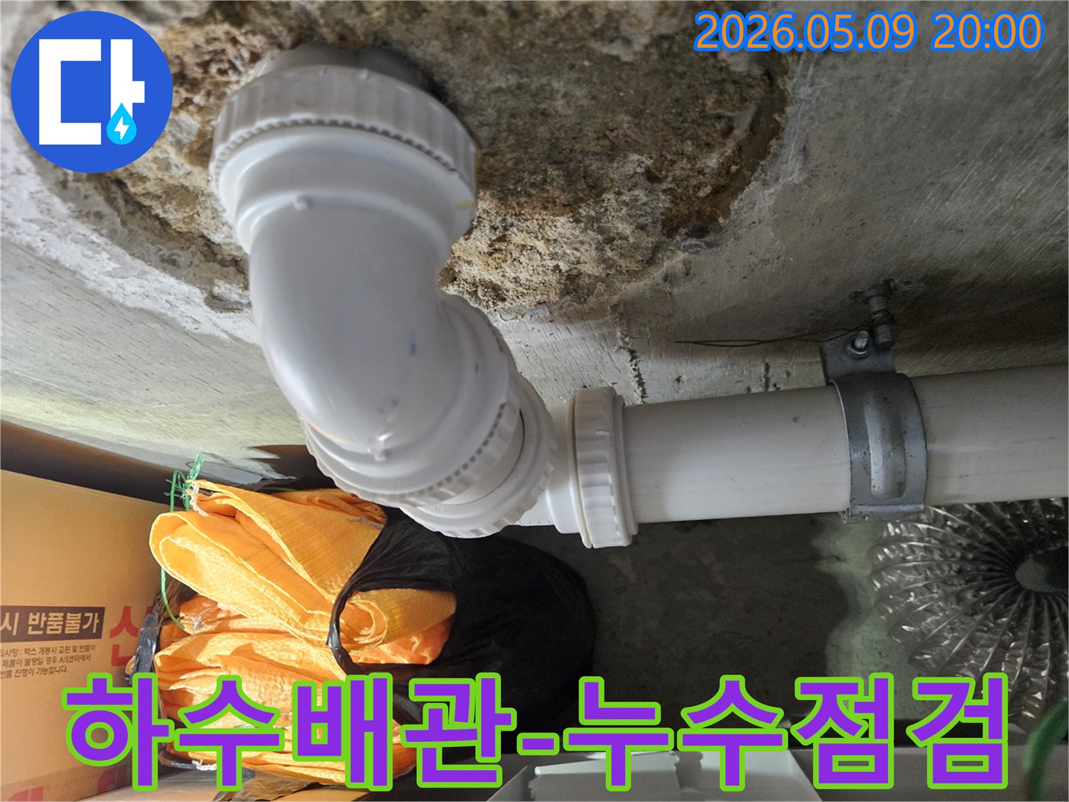 천장 콘크리트와 연결된 하수 배관의 접합부에서-누수 흔적을 발견하고-전문가가 정밀하게 점검하는 장면입니다