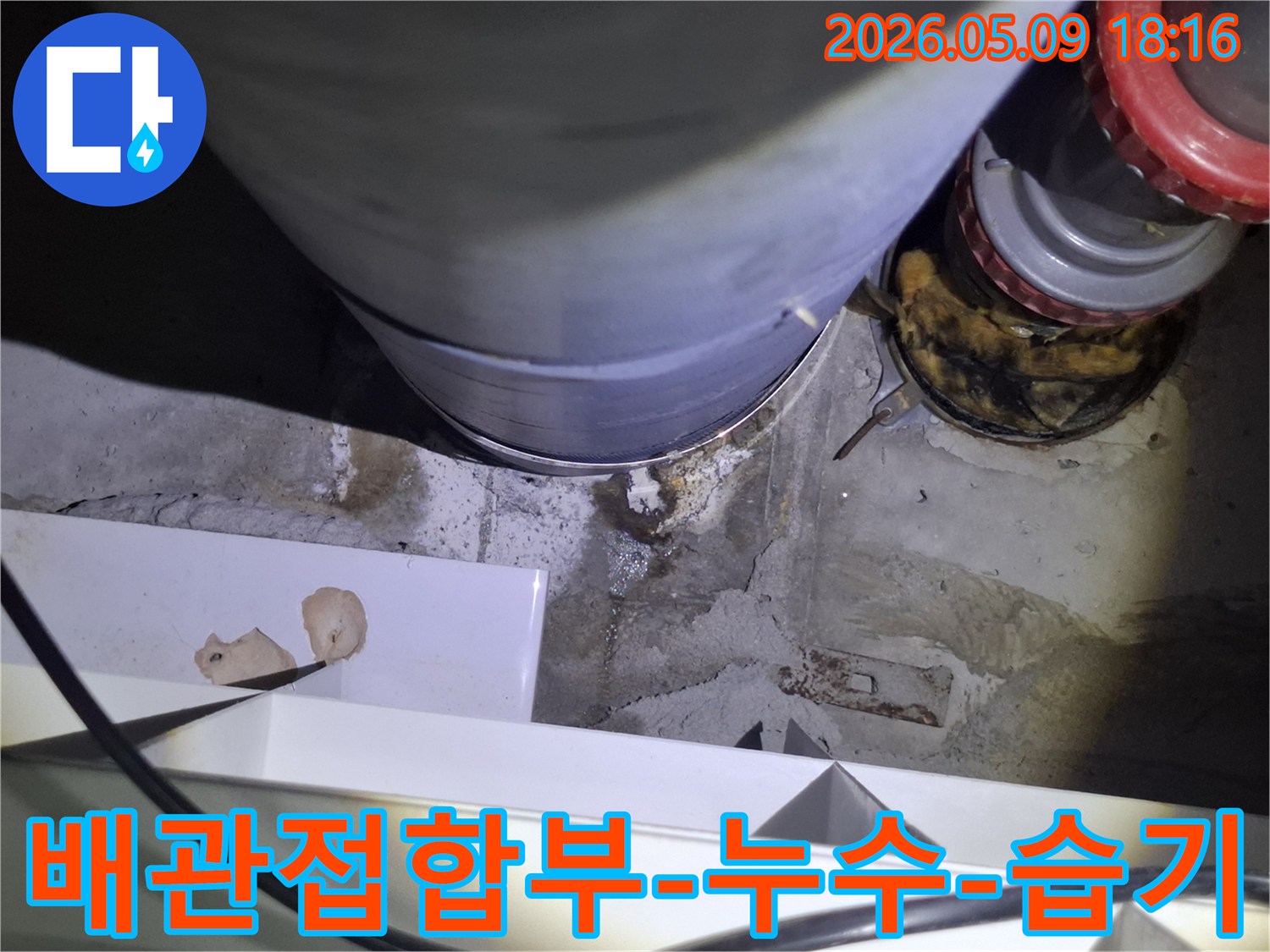 이 사진은-오래된 배관의-접합부에서-물이 새어-주변 콘크리트가-젖은-상태를-보여줍니다