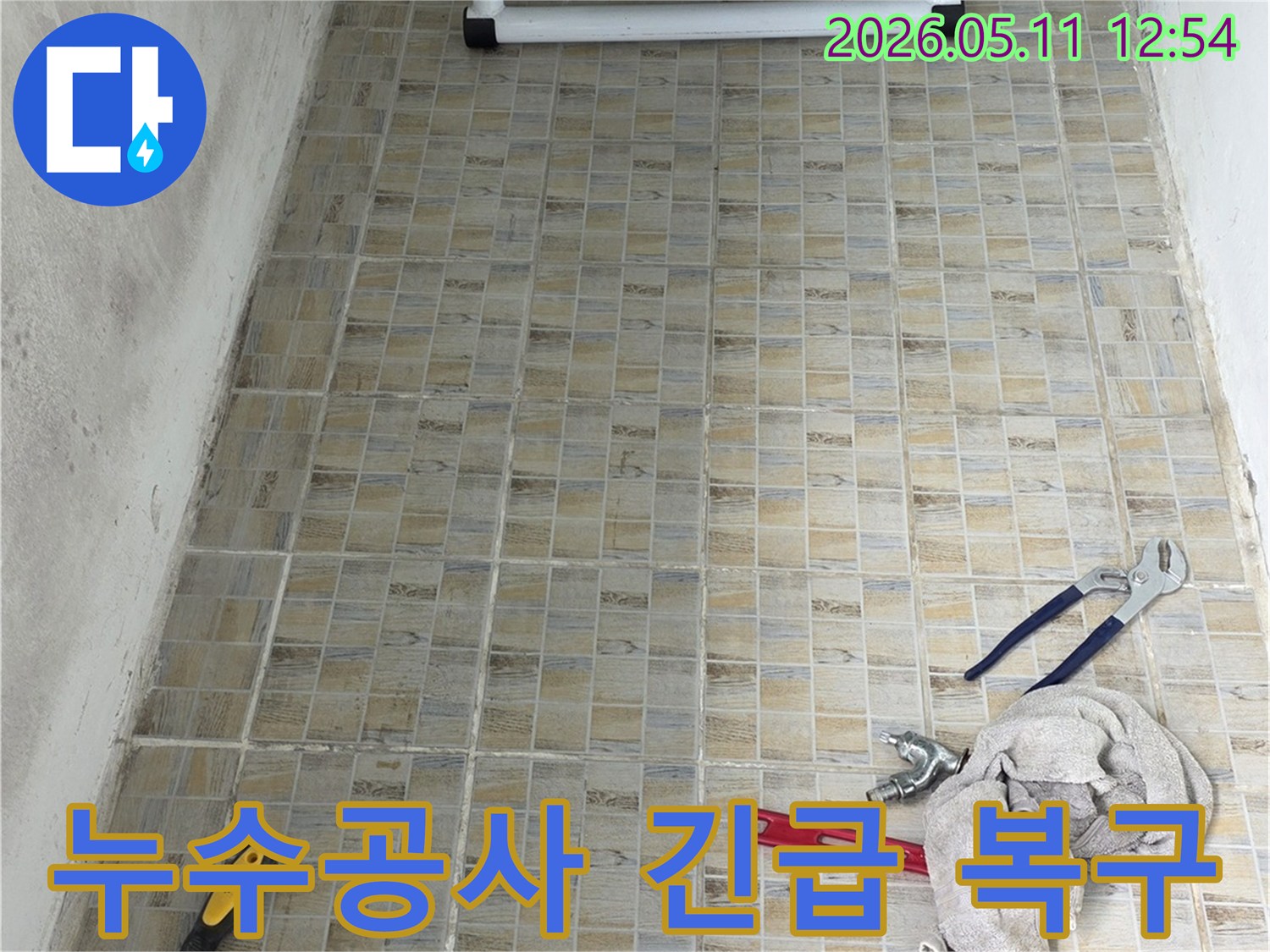누수 공사 현장에서-타일 벽면과-작업에 필요한 공구들이 놓여있는 모습