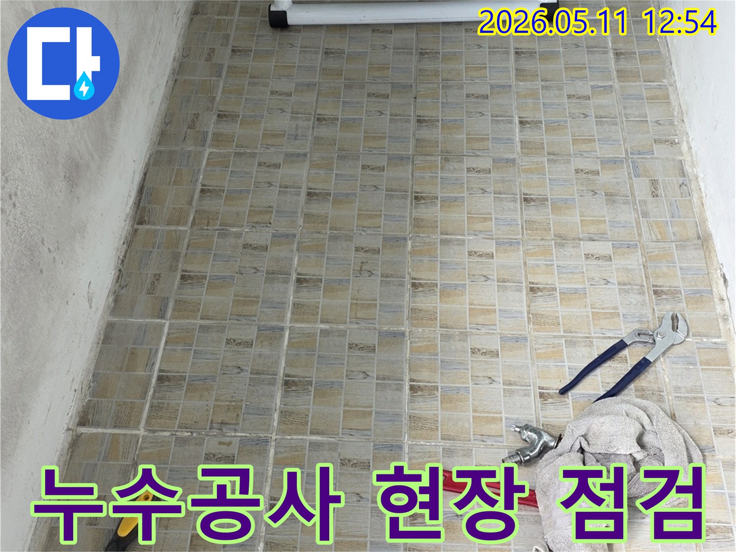 누수 공사 현장에서-타일 벽면과-작업에 필요한 공구들이 준비된 모습