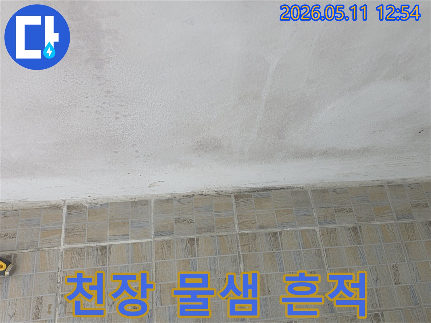 물샘-현상으로-인해-천장에-얼룩이-생긴-타일-벽면과-천장의-경계면을-보여주는-사진