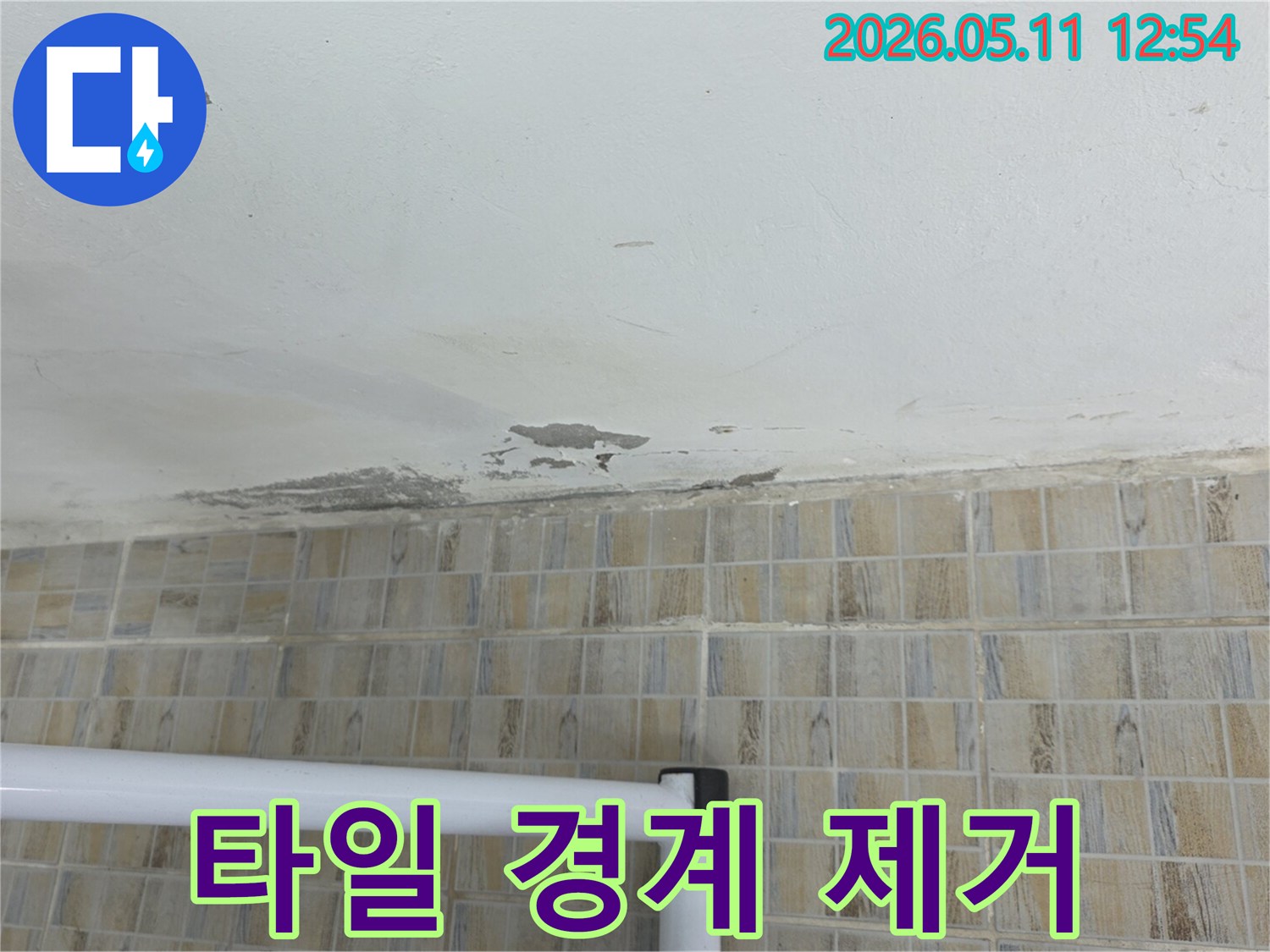 이 이미지는-천장과 벽면 타일의-경계 부위에-물이 스며들어 생긴-물기 흔적과-페인트 손상을-선명하게 보여줍니다