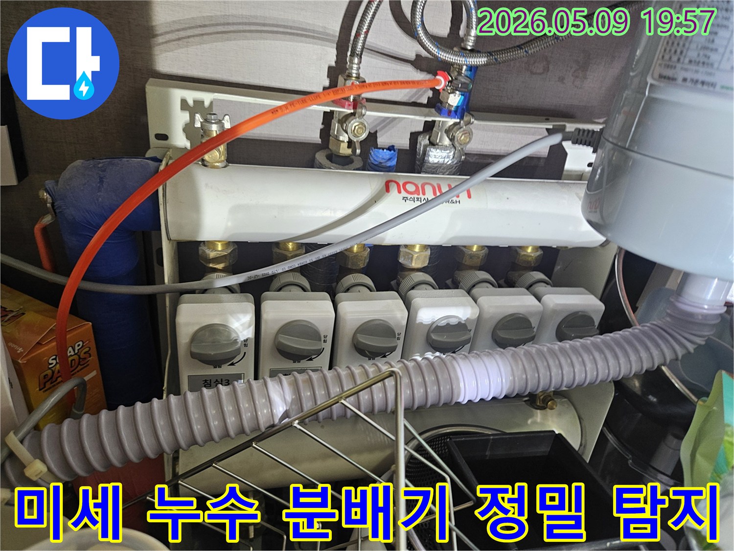 이 이미지는 보일러 분배기에서-육안으로 확인하기 어려운-미세한 누수를 찾아내기 위해-정밀 탐지 장비를 사용하는 장면입니다.