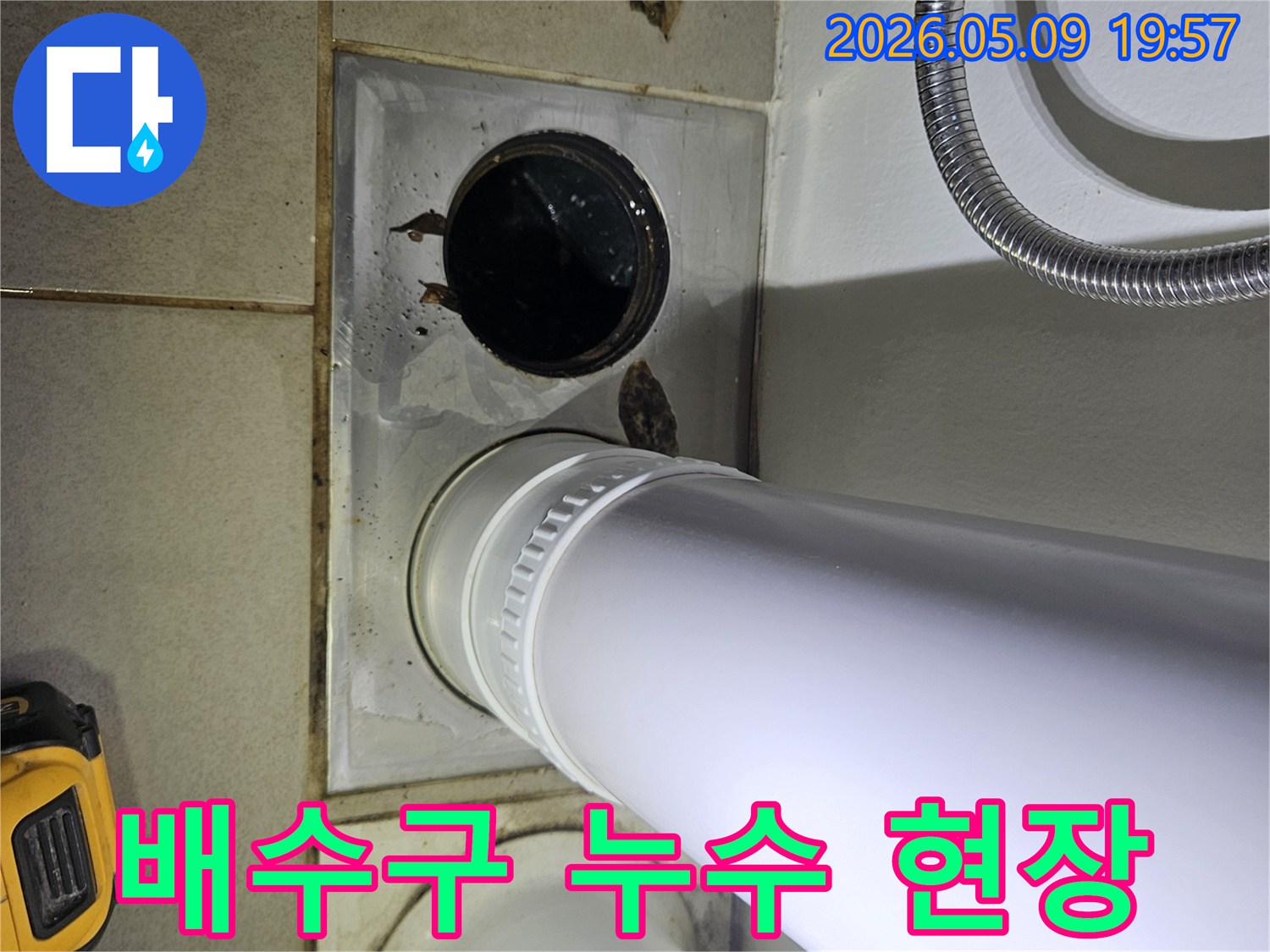 이 이미지는 욕실 바닥의 배수구와 인접한 배관에서 발생한 물 고임 현장을 보여주며-누수 가능성을 시사합니다.