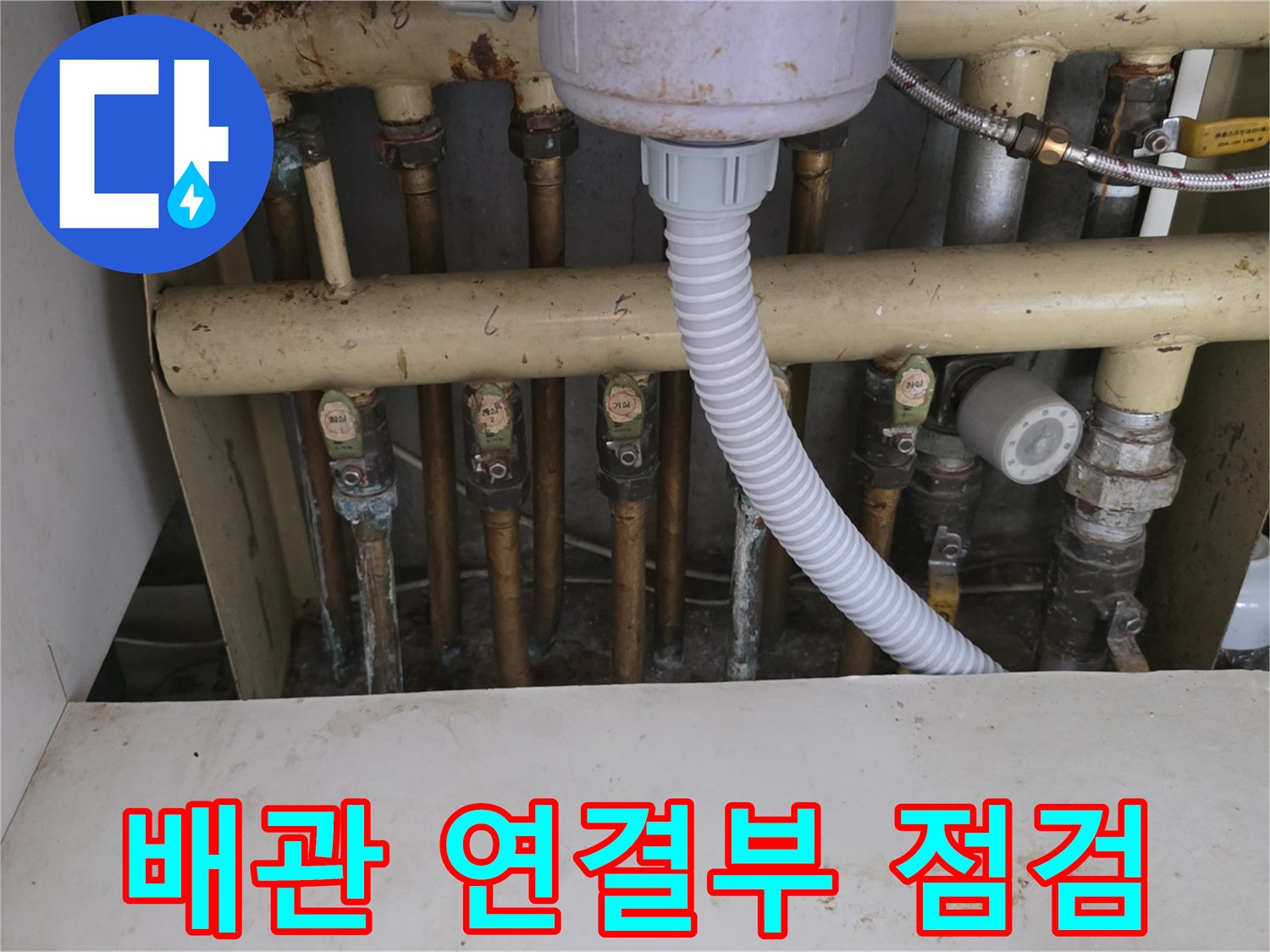 보일러 분배기의 금속 너트와 배관 접합부를 정밀하게 점검하는 모습입니다.