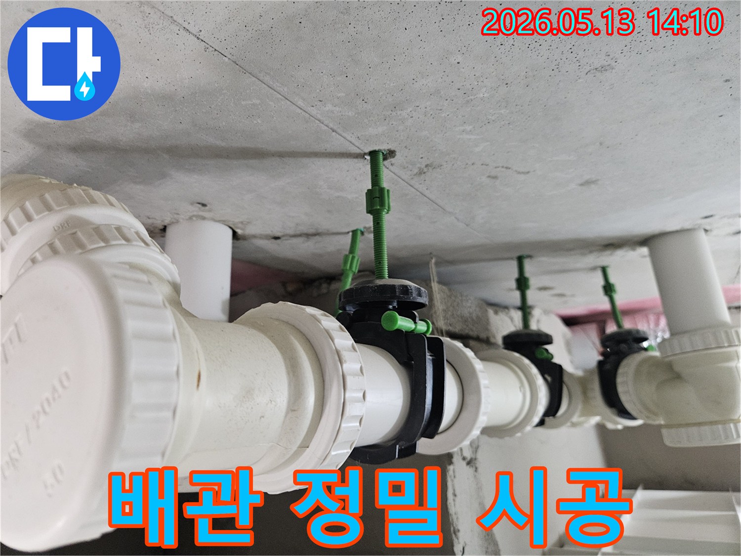 콘크리트 천장에 정확한 간격으로 설치된 흰색 배관과-정교하게 연결된 검은색 밸브의 모습