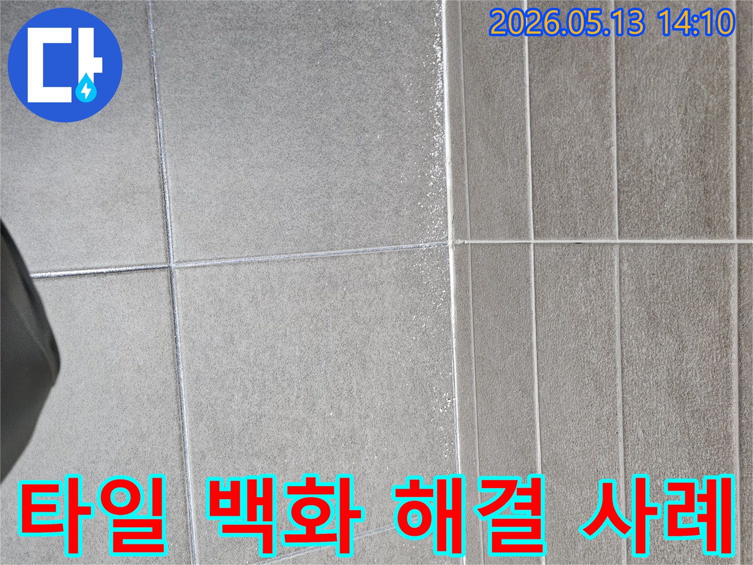회색 타일 벽과 바닥의 접합부에-하얗게 나타난 백화 현상은-누수 탐지 후 해결된-성공적인 사례를 보여줍니다.