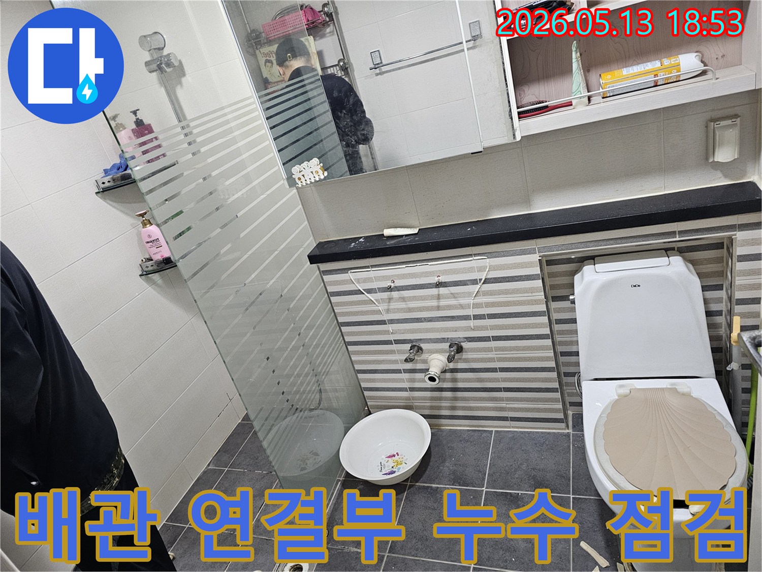 이 이미지는-인천 럭키송도아파트 화장실에서-배관 연결 부위의 누수 여부를-확인하기 위해-세면대를 분리하고-배관을 점검하는 현장입니다.