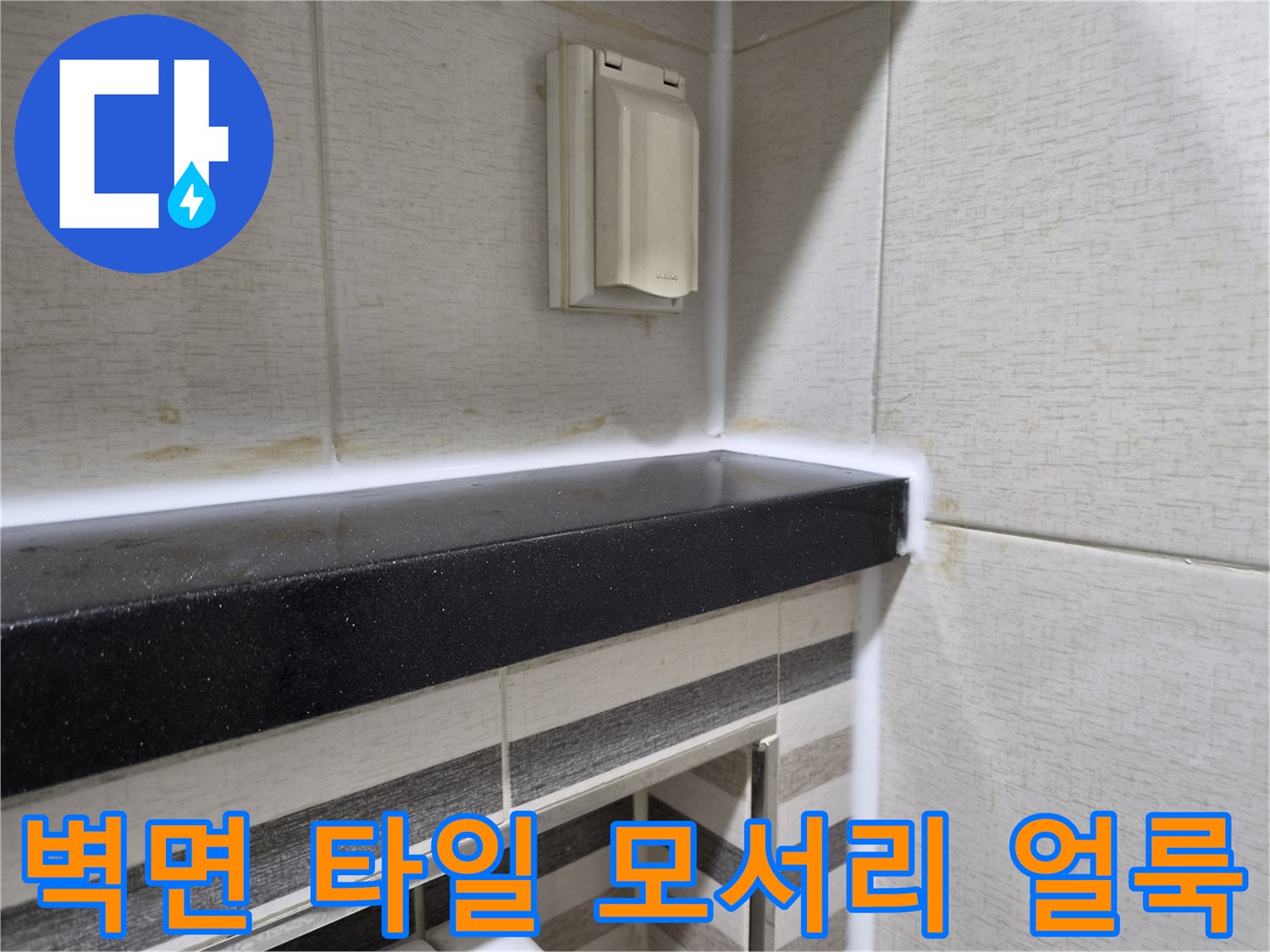 타일과 선반 경계 부분의 습기 변색 상태를 촬영한 이미지입니다.