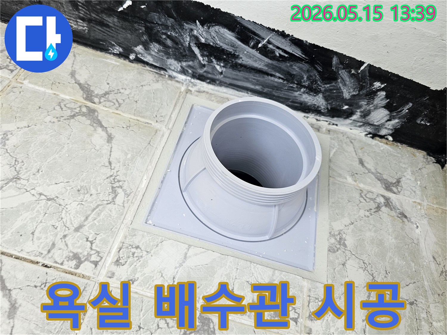욕실 바닥에 설치된 새로운 배수관 연결 부품과-주변 방수 처리된 벽면 하단부의 모습-누수 예방을 위한 정밀 시공