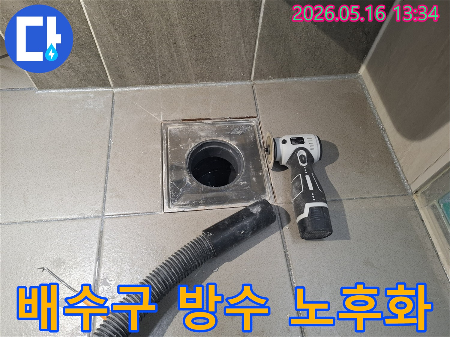 누수 엔지니어가 욕실 배수구 주변의 방수층 노후화로 인한 누수를 해결하기 위해-전동 공구로 표면을 정리하고-흡입 호스로 현장을 깨끗하게 만드는 중입니다