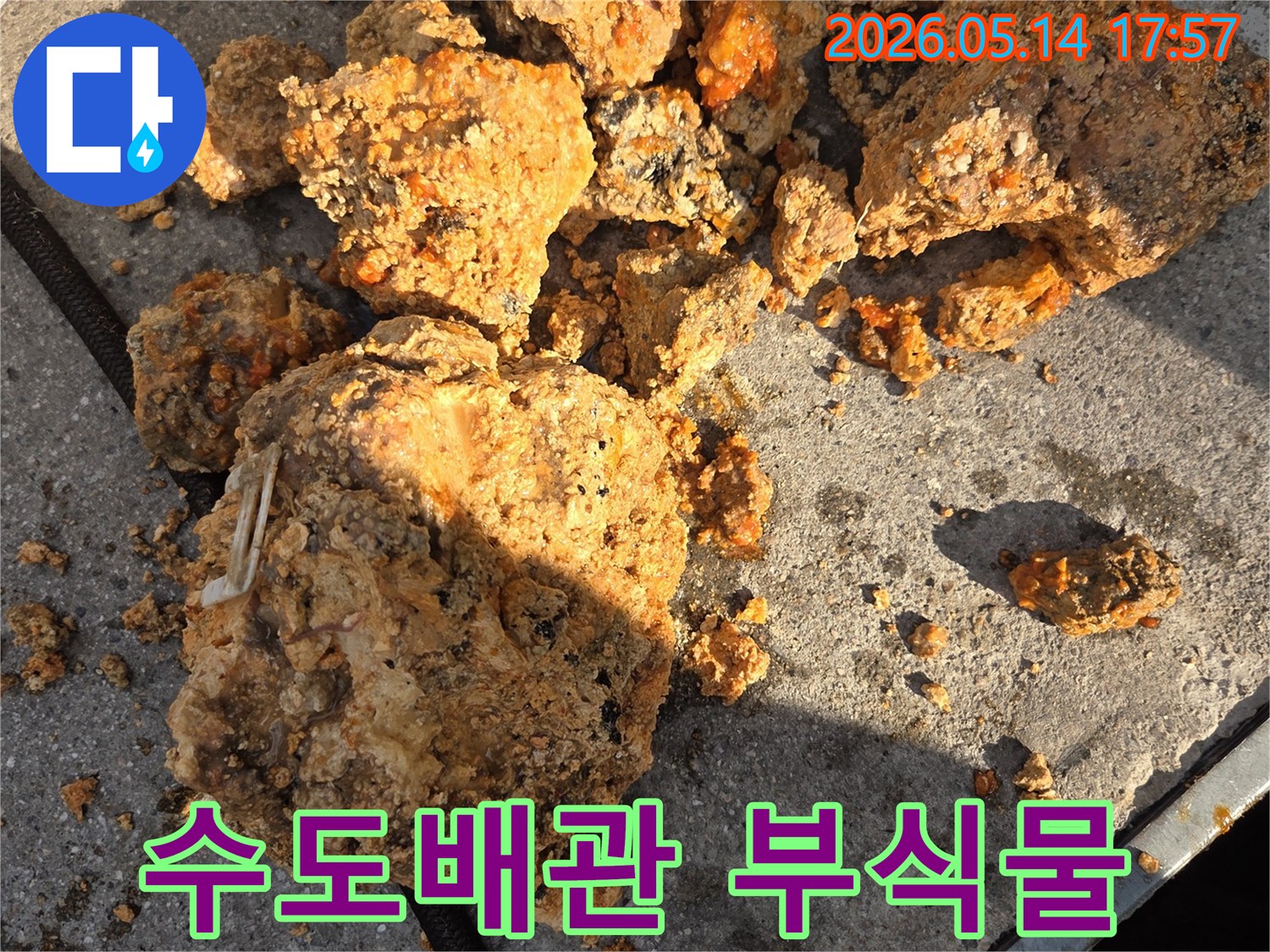 이 이미지는-부식된 수도배관에서-제거된-녹물과-스케일 덩어리들을-가까이서 보여줍니다