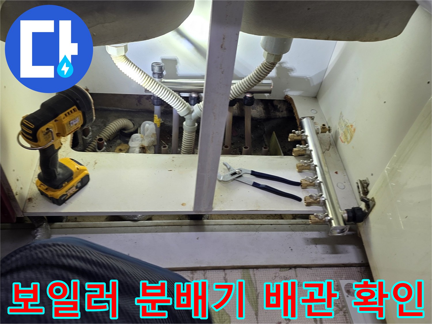 싱크대 하단에 위치한 보일러 분배기와 각 배관의 연결 상태를 촬영한 사진입니다