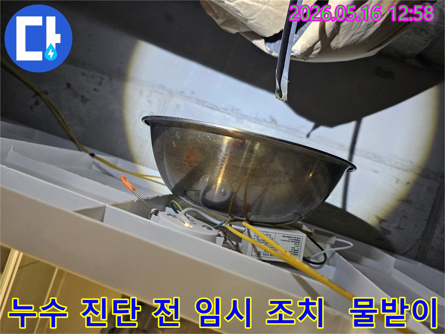 누수 진단 작업을 시작하기 전-천장에서 물이 떨어지는 것을-스테인리스 볼로-받아내며-주변의 전기 배선과-조명 장치를-보호하는 모습