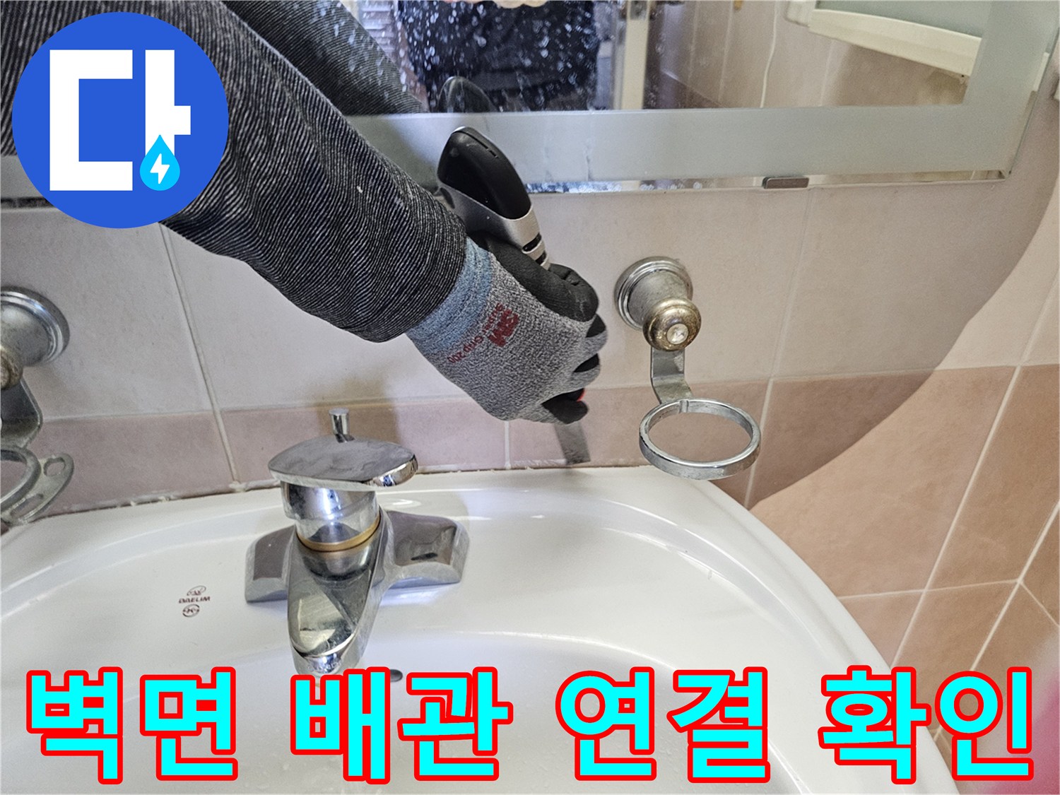 벽면에 돌출된 배관과 수전의 결합 상태를 점검하는 작업자