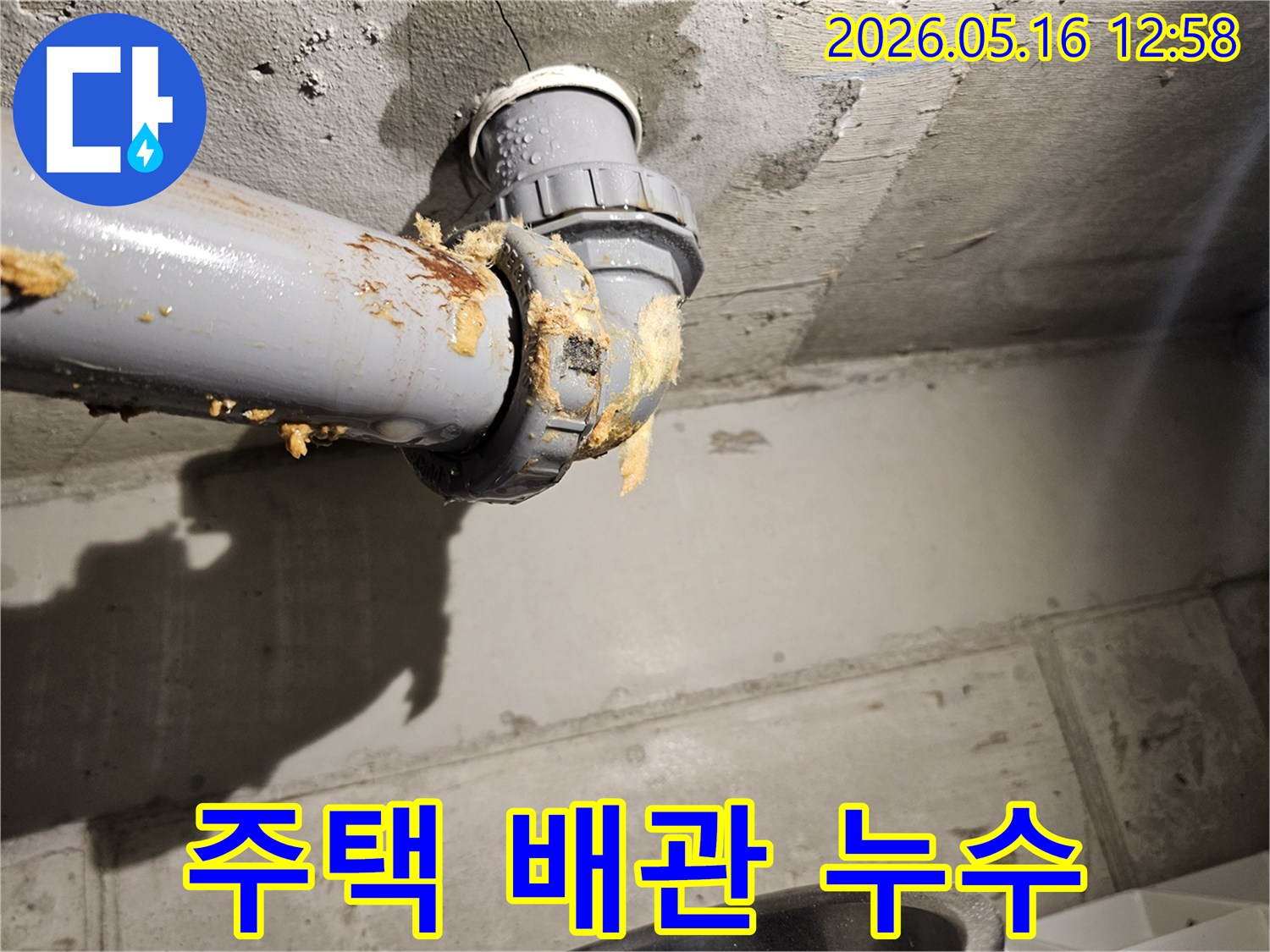주택-천장-아래-배관-연결부에서-물이-새어-나와-단열재가-젖은-모습을-보여주는-누수-현장-사진