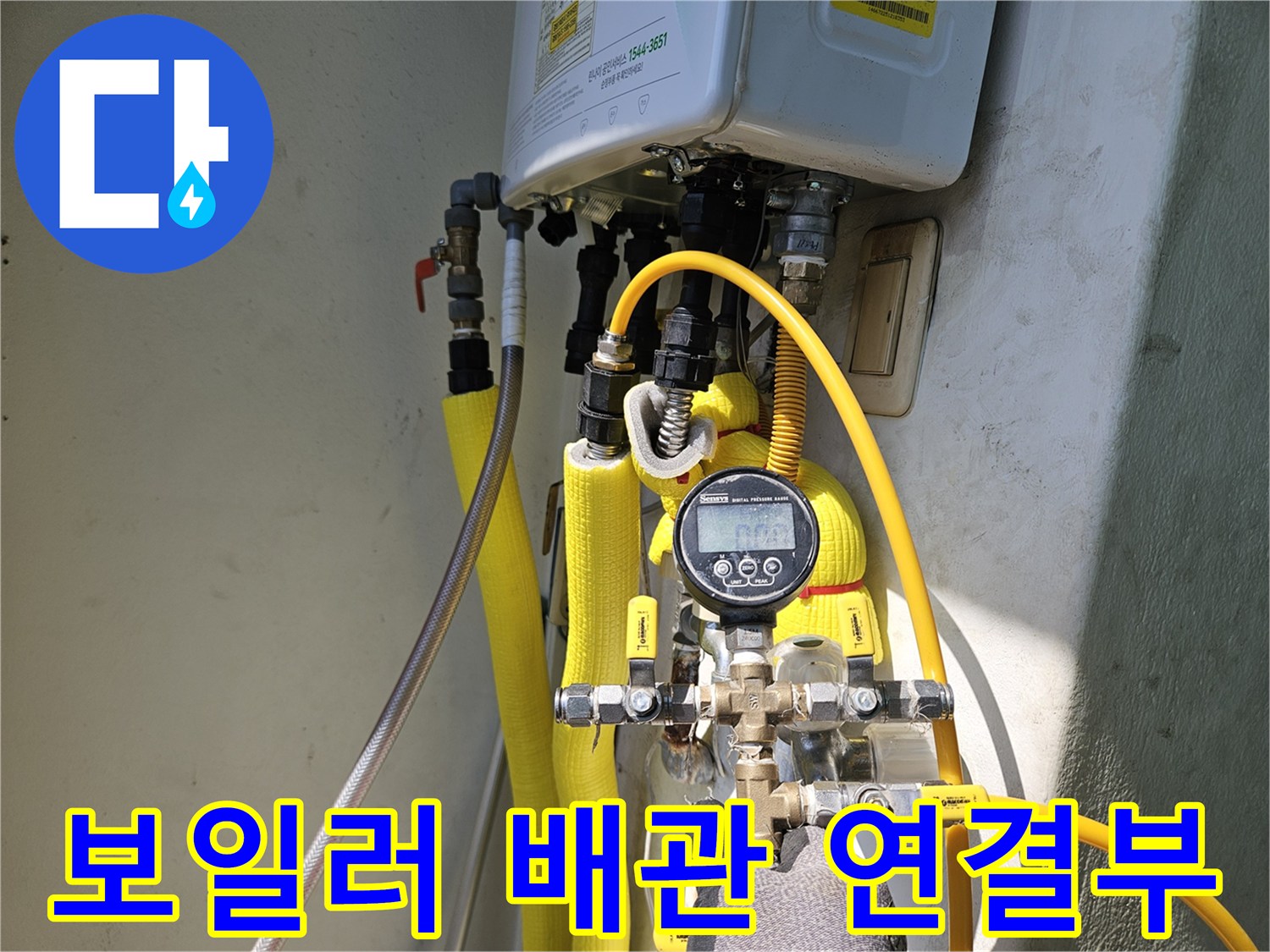 노란색 보온재로 감싸진 보일러 하단 온수 및 냉수 배관 연결 부위