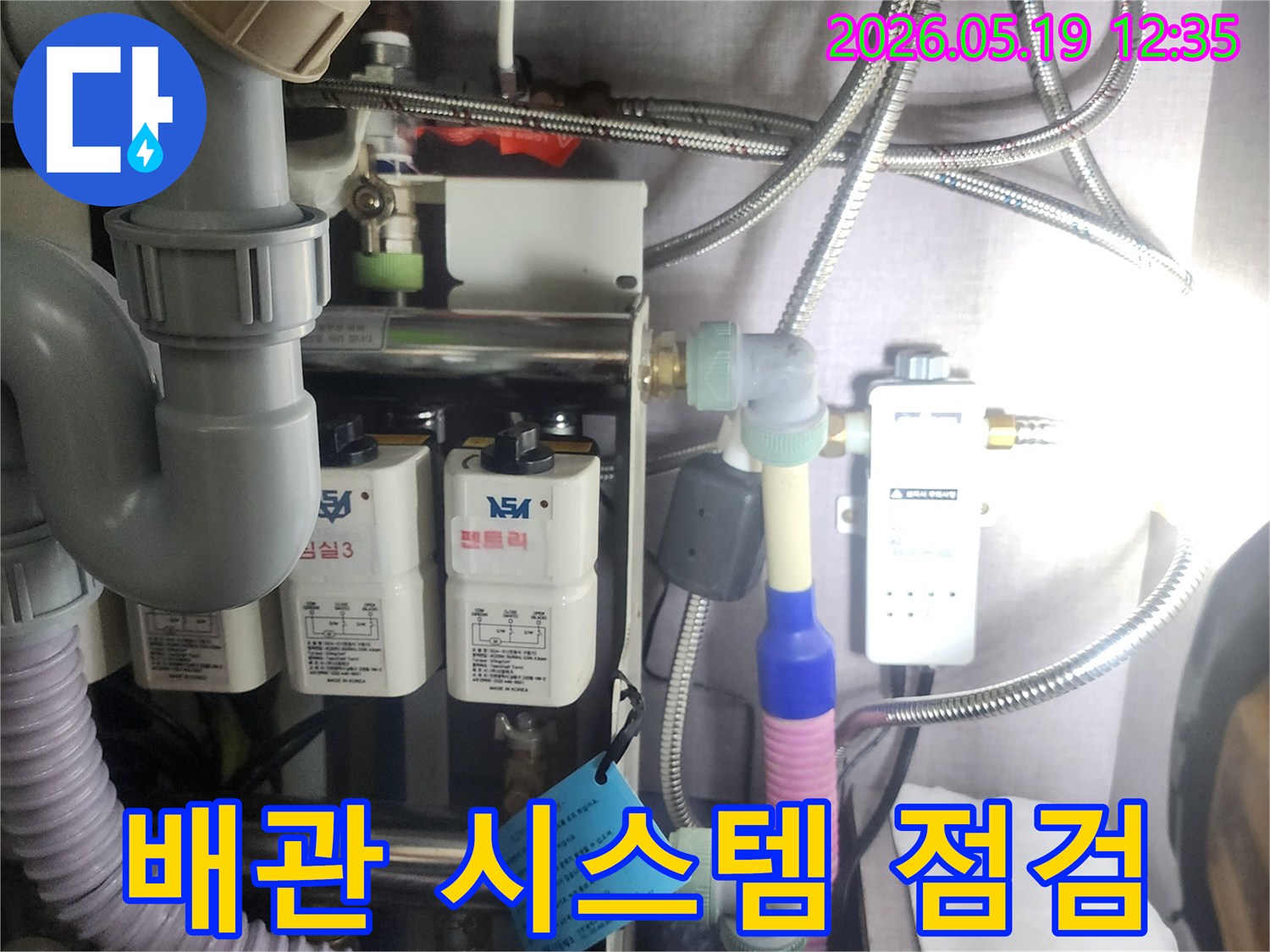 누수 문제를-해결하기 위해-복잡하게 연결된-수도 배관과-정수 장치를-전문가가-면밀히-살펴보는-장면입니다.