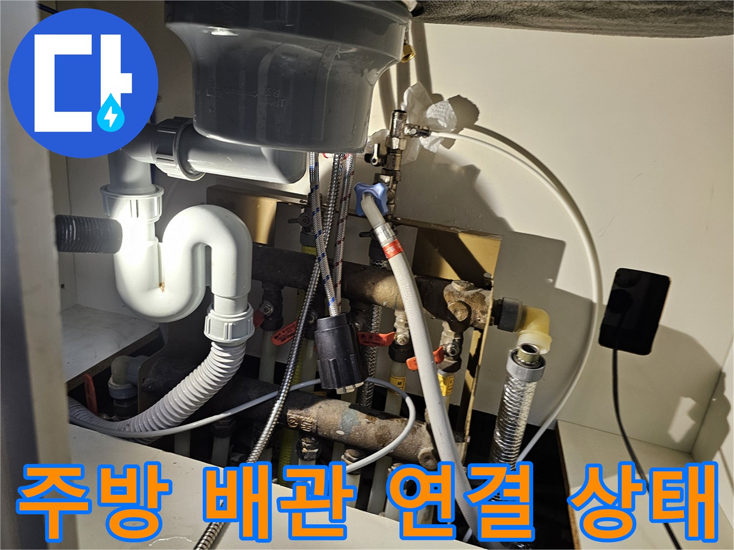싱크대 하부의 급수 호스와 배수 트랩 연결 부위 상세 사진