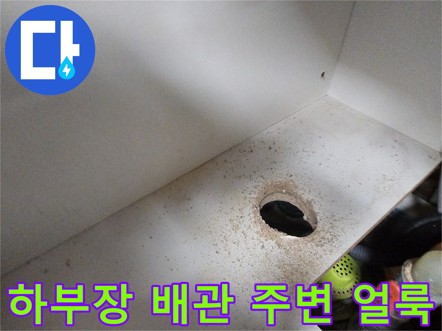 싱크대 하부장 바닥 배수 구멍 근처의 습기와 오염 상태를 보여주는 사진