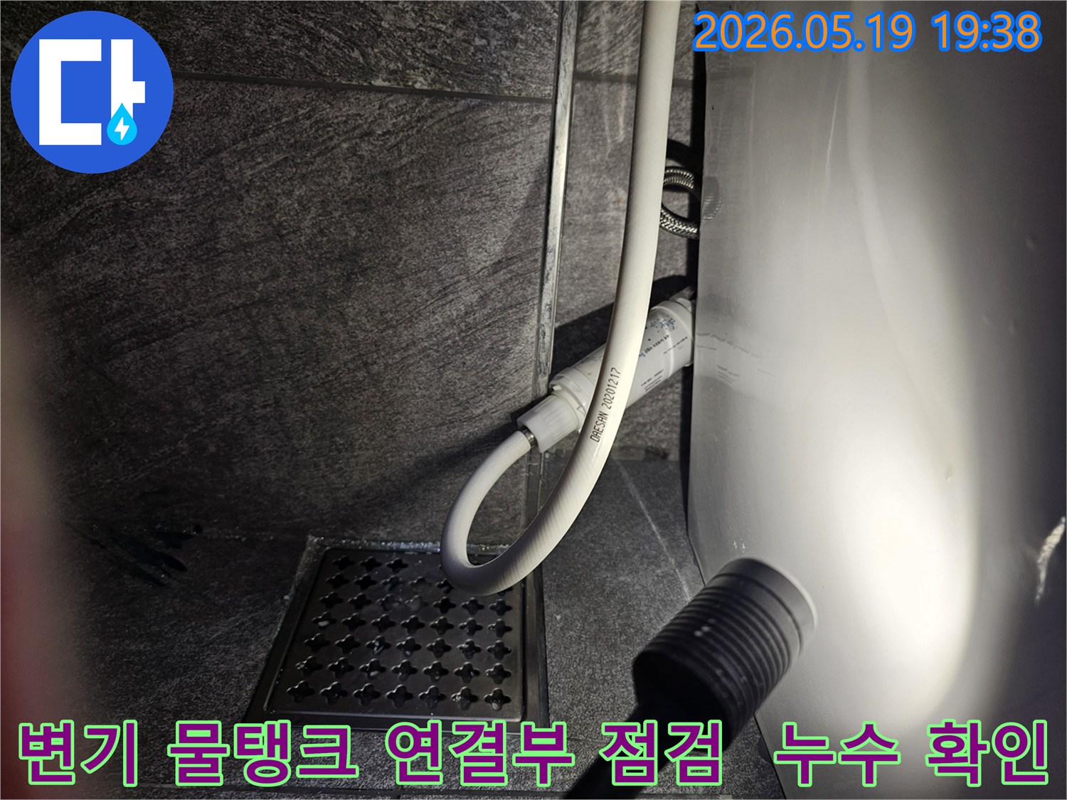 이 이미지는-용인 수지 아파트 화장실에서-변기 물탱크 연결부의 누수 여부를-플래시로 비추며-세밀하게 점검하는 현장을 보여줍니다.